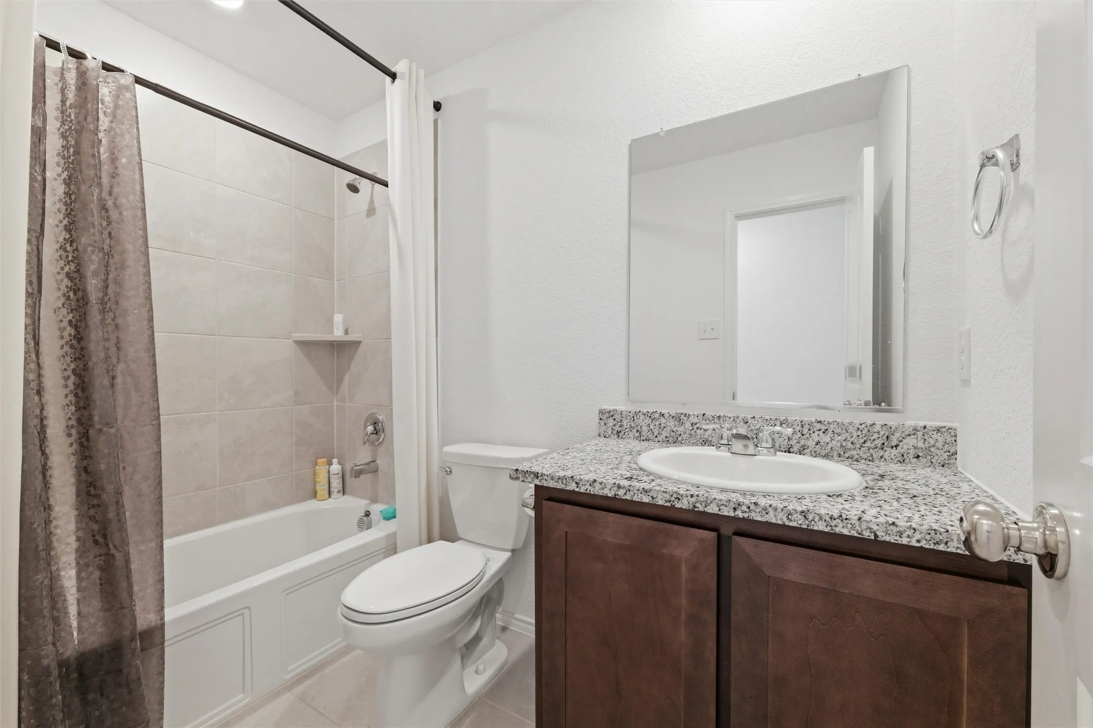 Bathroom featuring vanity, shower / bathtub combination with curtain, and light tile patterned floors