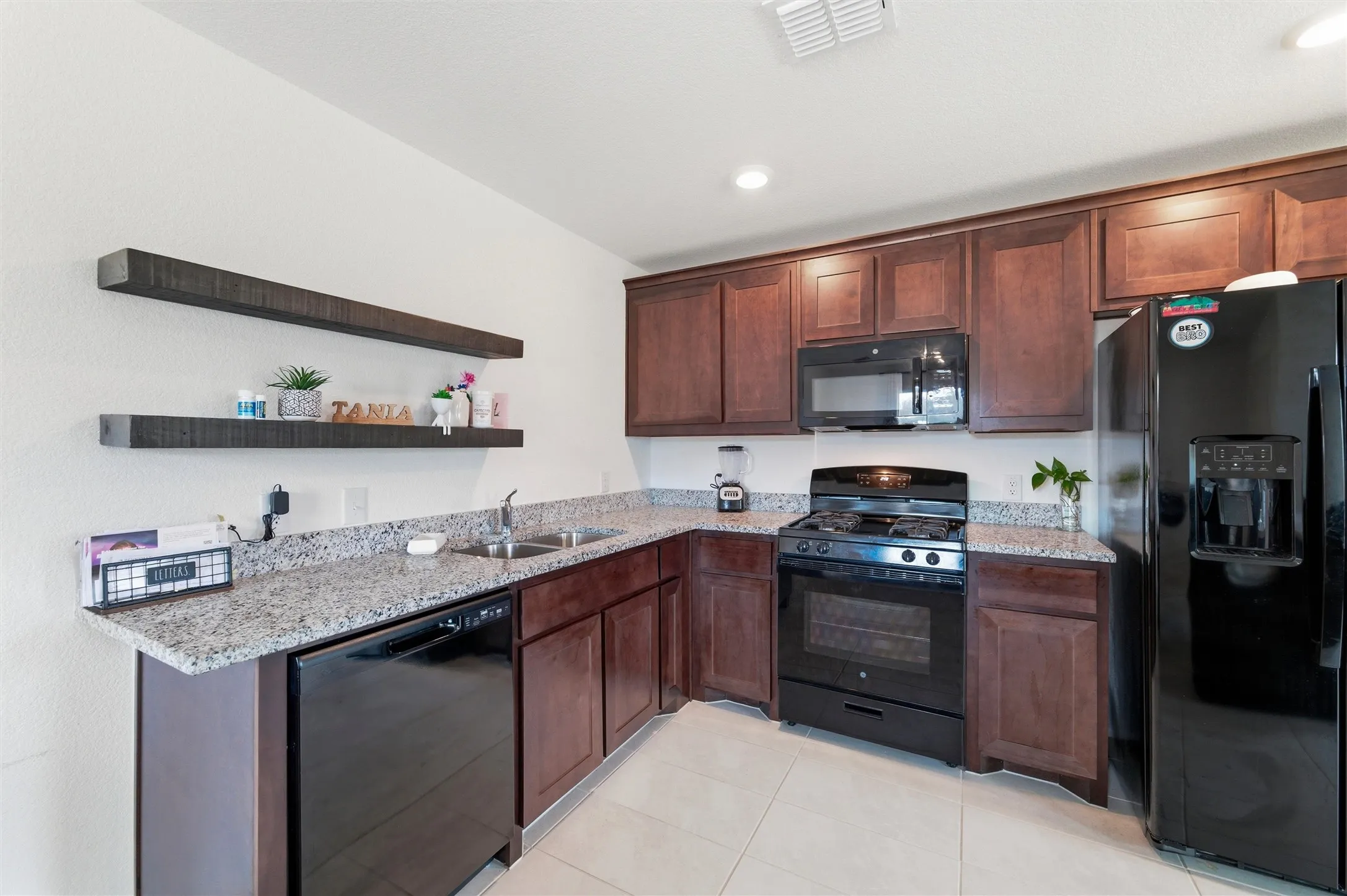 Kitchen with black appliances, light stone counters, open shelves, light tile patterned floors, and recessed lighting