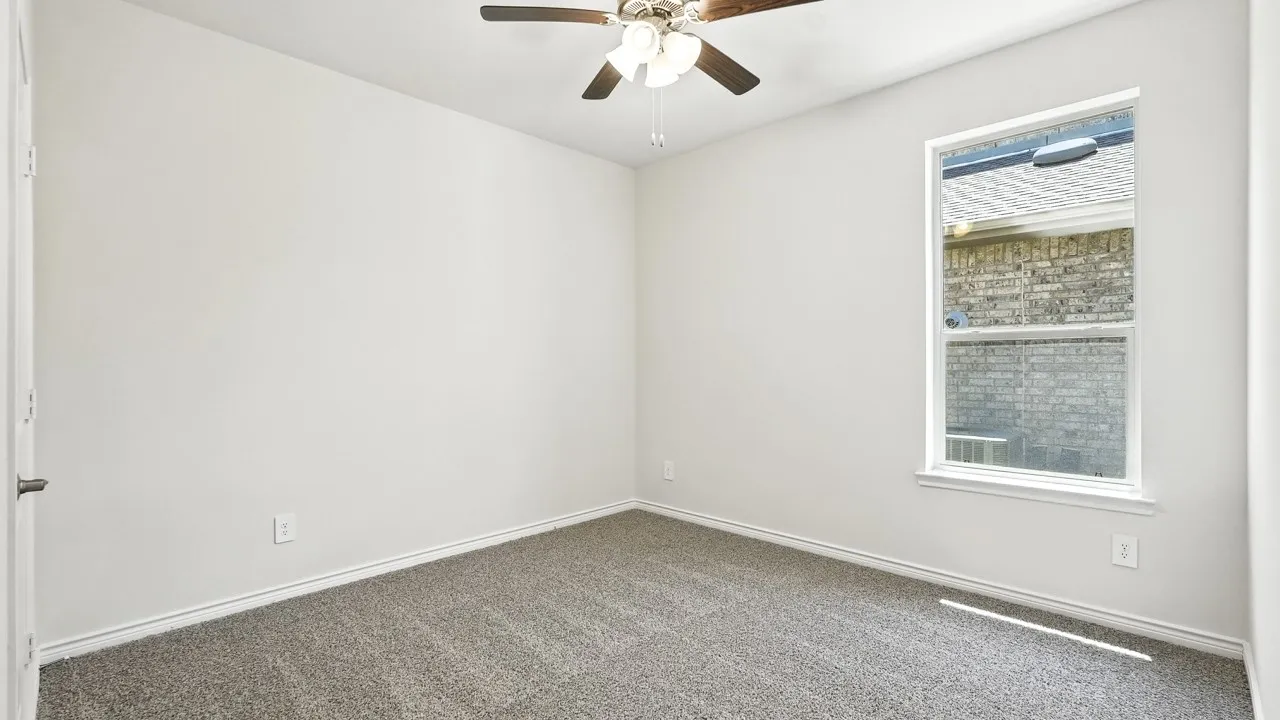 Empty room featuring dark carpet and a ceiling fan