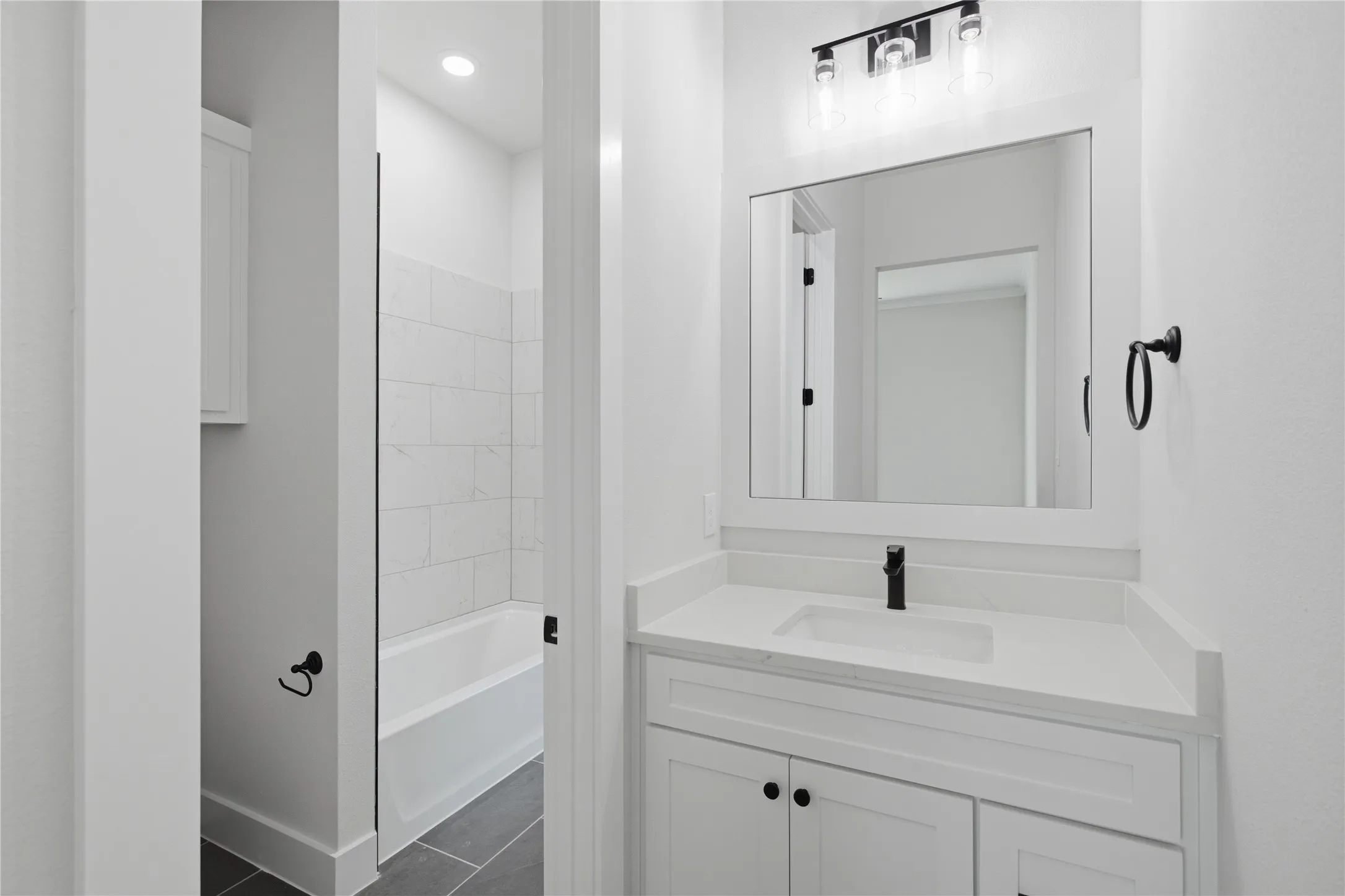 White vanity with a rectangular undermount sink, a countertop, and a matte black faucet