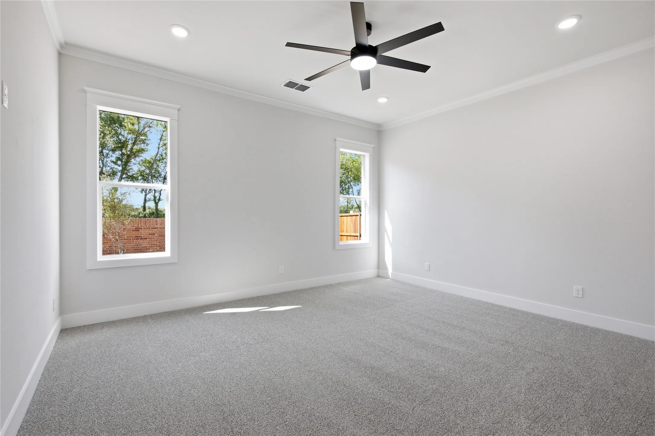 Plush gray carpeting, dual recessed lighting, and a modern ceiling fan with integrated lighting