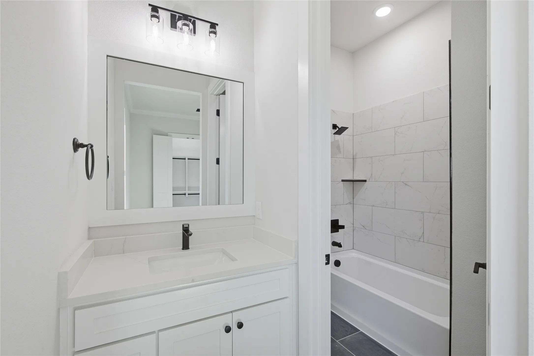 Bathroom featuring a white vanity with a rectangular sink, a matte black faucet, and a large wall-mounted mirror