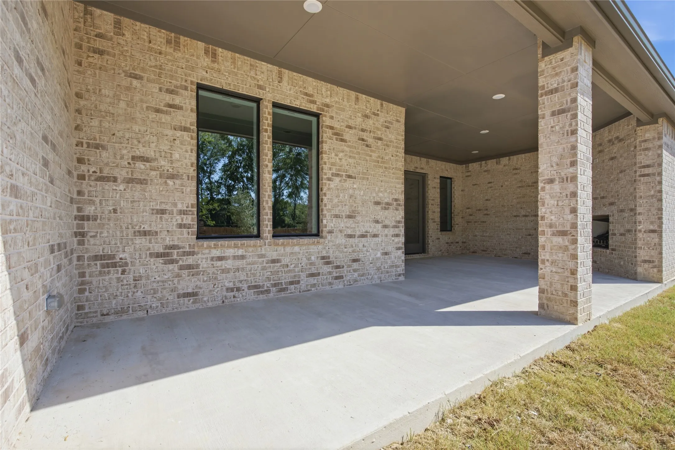 Covered patio with a brick exterior, recessed lighting, and an outdoor fireplace
