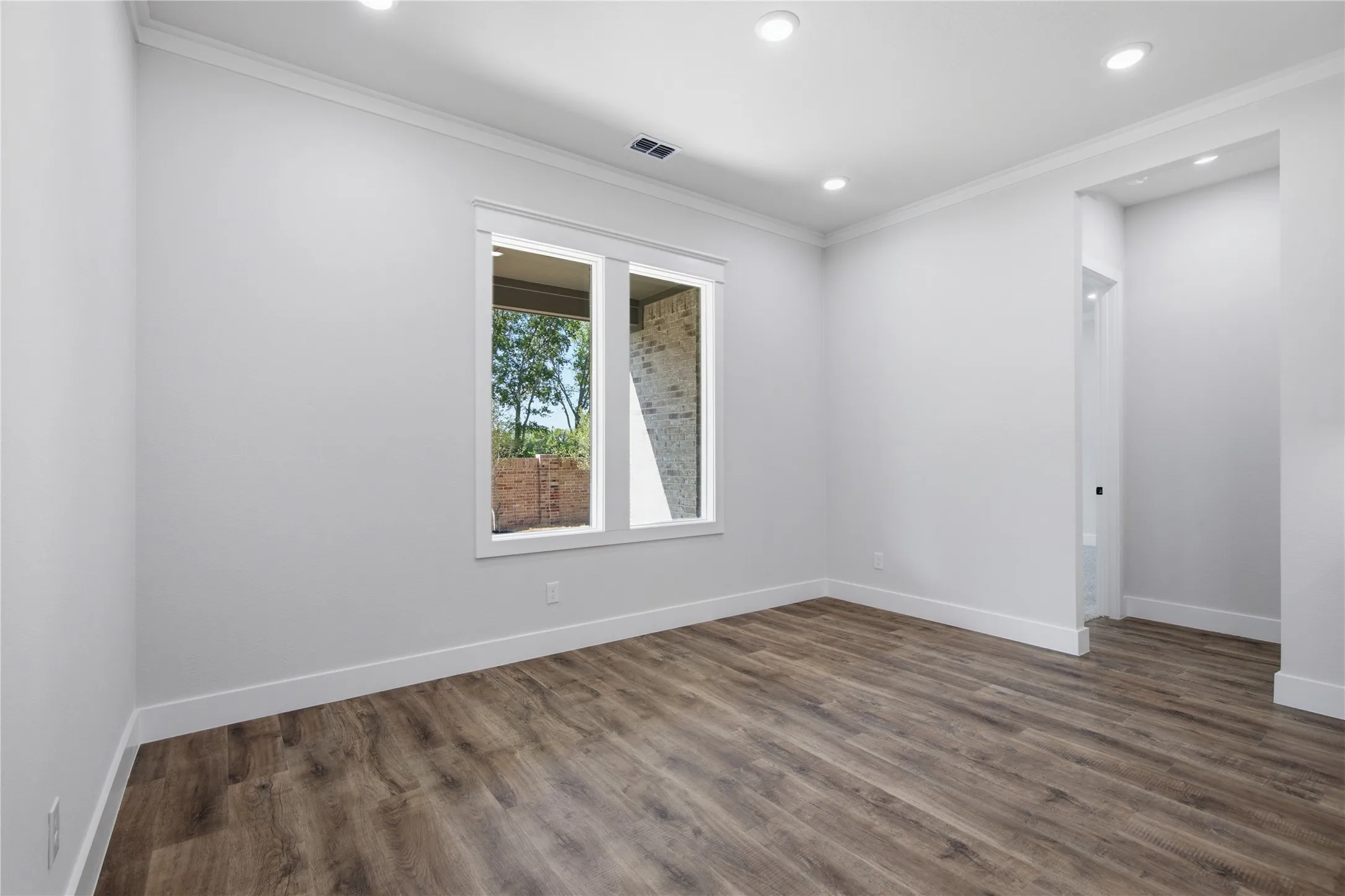 Recessed lighting, wood-finish flooring, white trim, and a window with a white frame