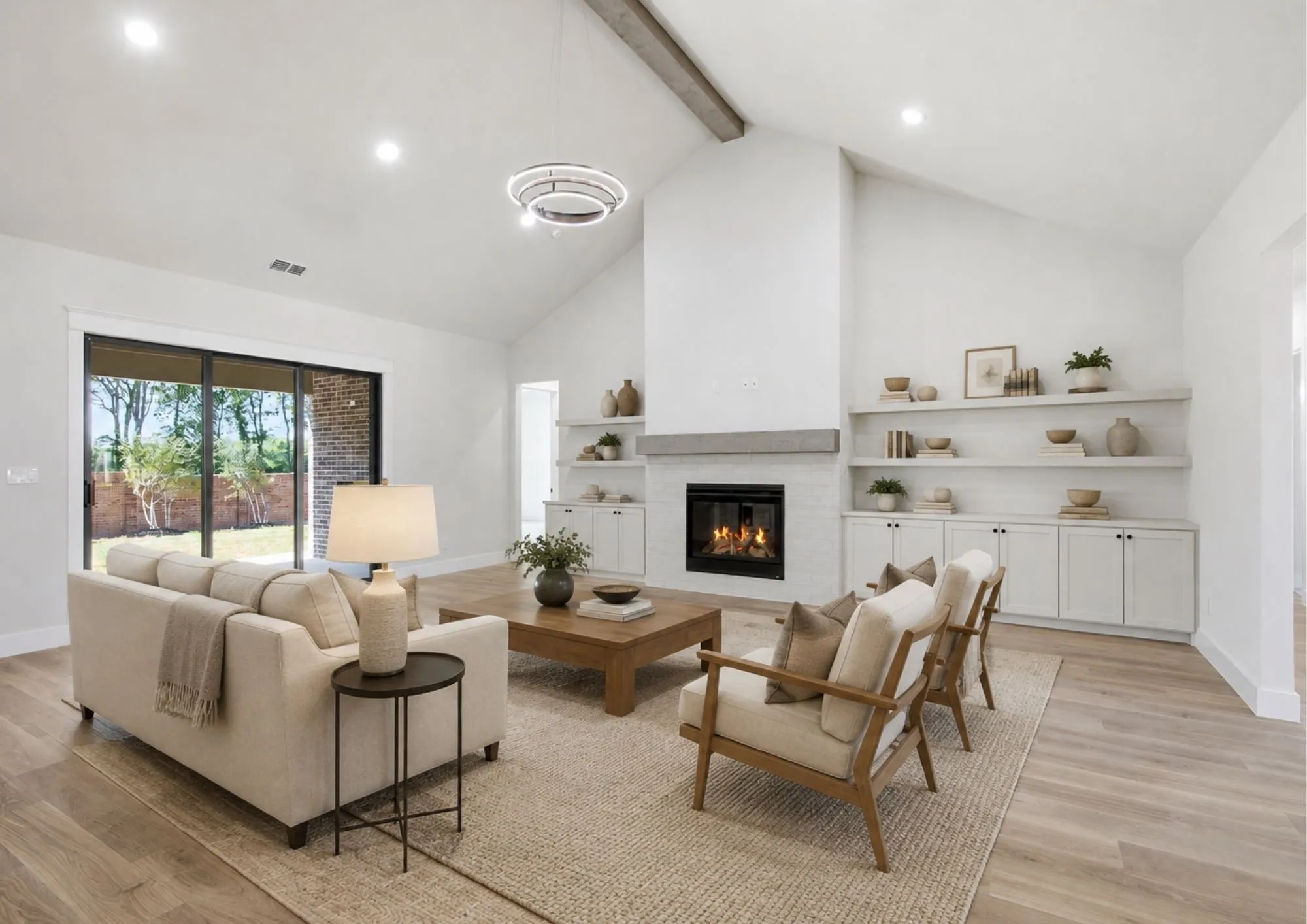 Virtually Staged.  Vaulted ceiling with exposed wood beam, modern fireplace, built-in cabinetry, and sliding glass doors to the exterior
