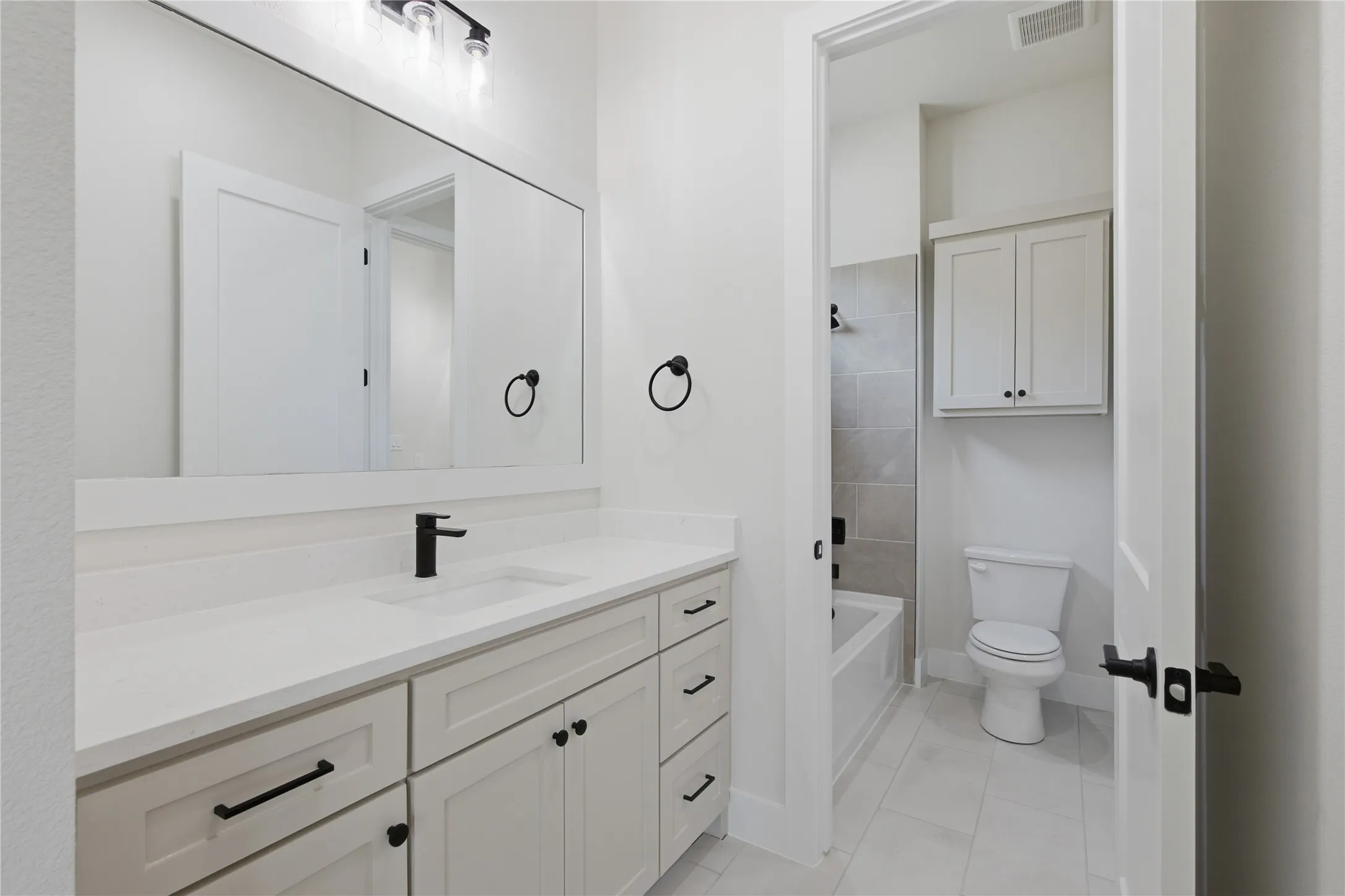 White shaker-style vanity with an integrated sink and matte black faucet