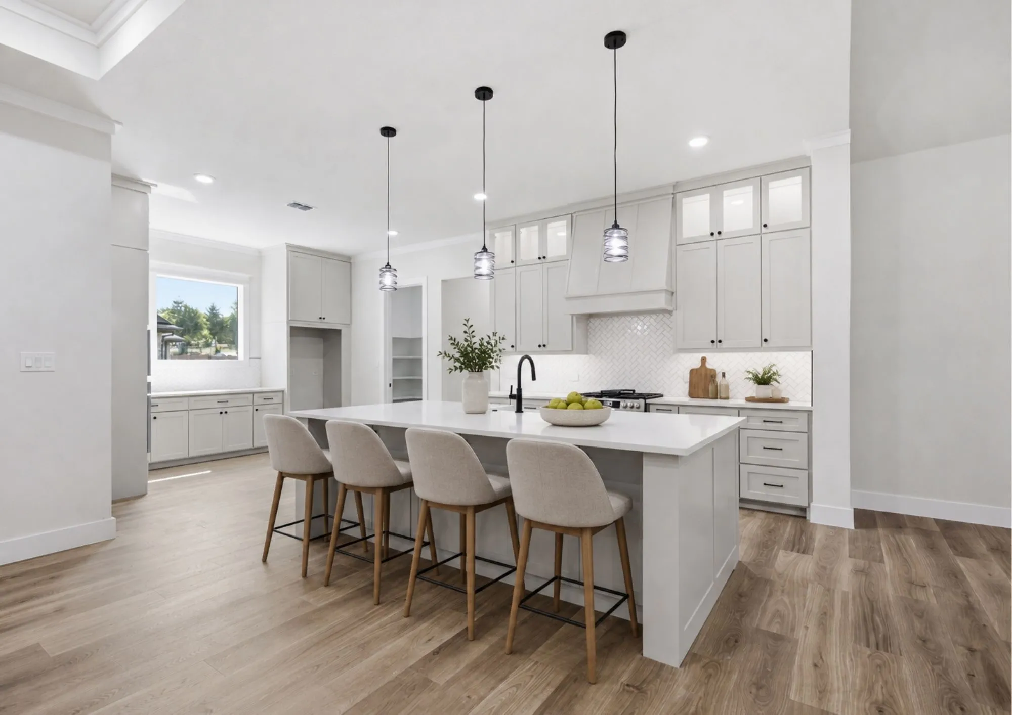 Virtually Staged. Spacious kitchen featuring an expansive central island with seating, pendant lighting, white cabinetry, integrated range hood, and wood-finish flooring