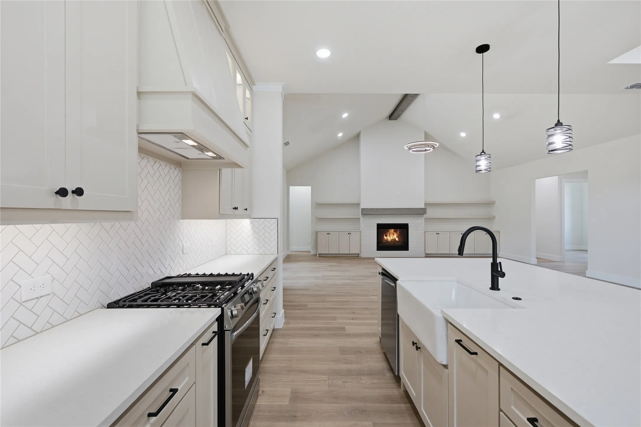 Kitchen with a gas range, white cabinetry, herringbone tile backsplash, and a farmhouse sink