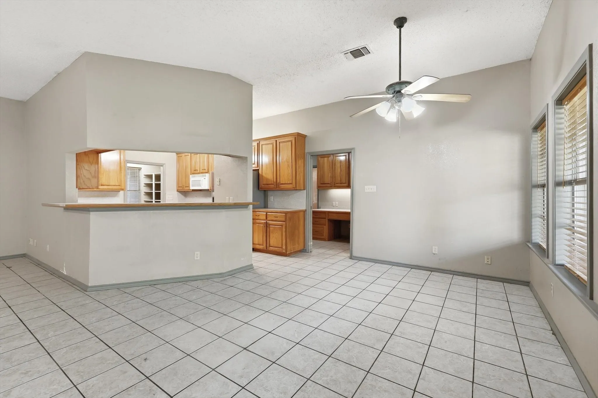 Unfurnished living room featuring lofted ceiling, a ceiling fan, and light tile patterned flooring