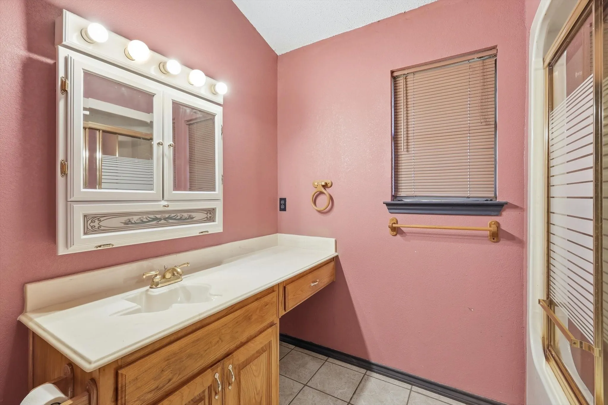 Bathroom with vanity, light tile patterned flooring, and lofted ceiling