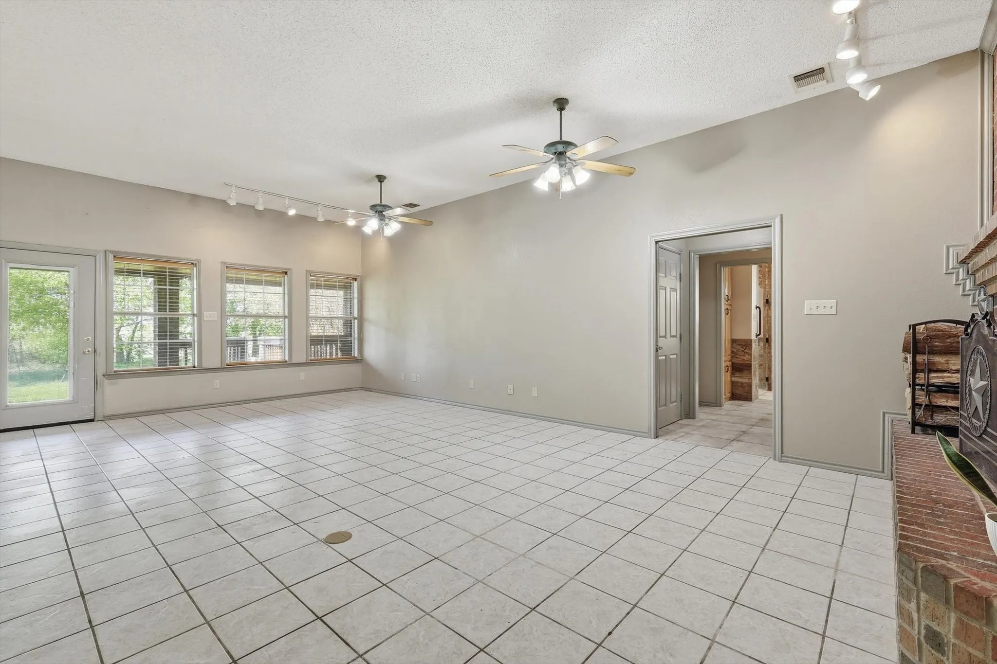 Spare room with track lighting, light tile patterned flooring, a textured ceiling, and ceiling fan