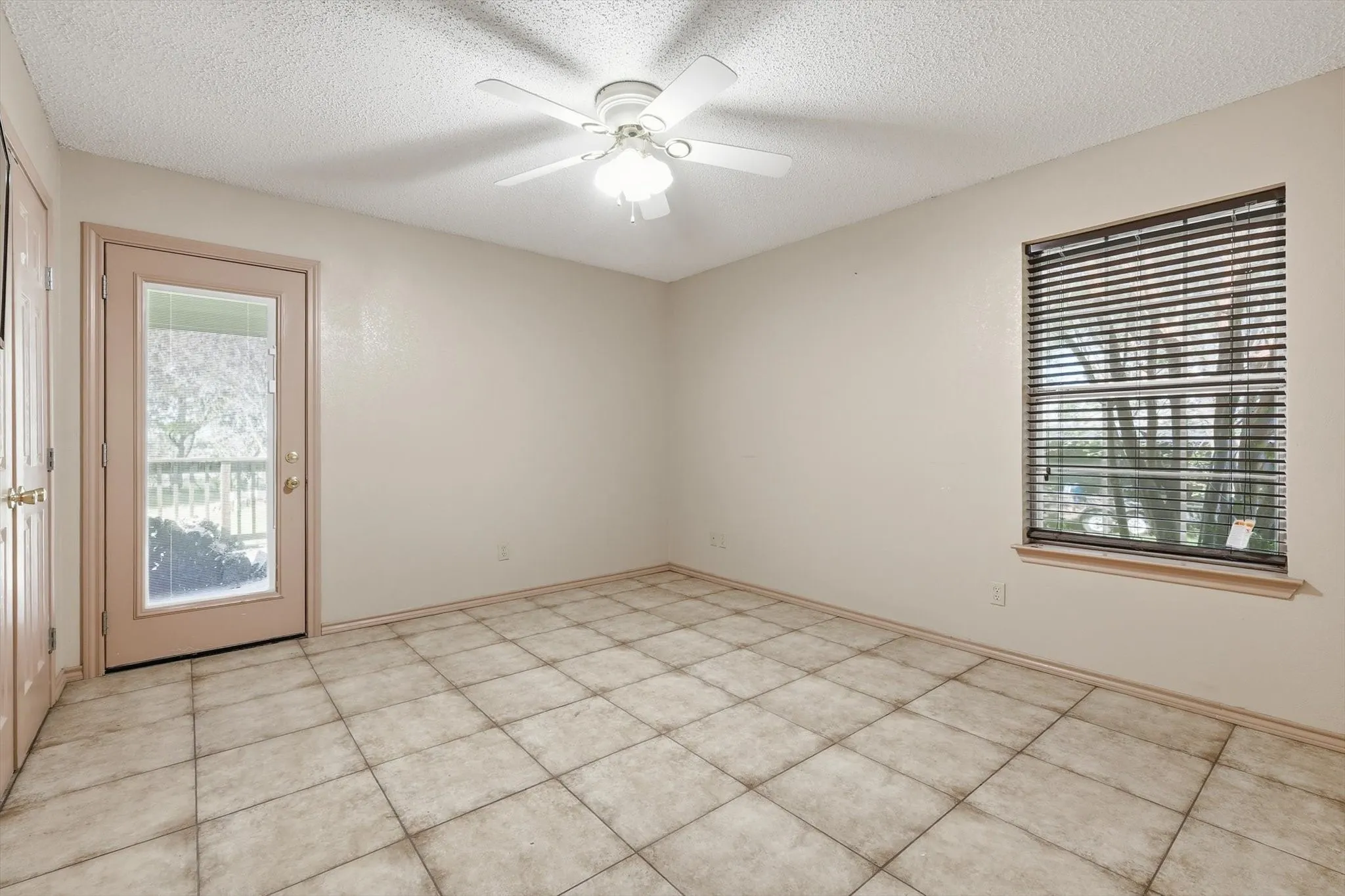 Spare room with a ceiling fan, a textured ceiling, and healthy amount of natural light