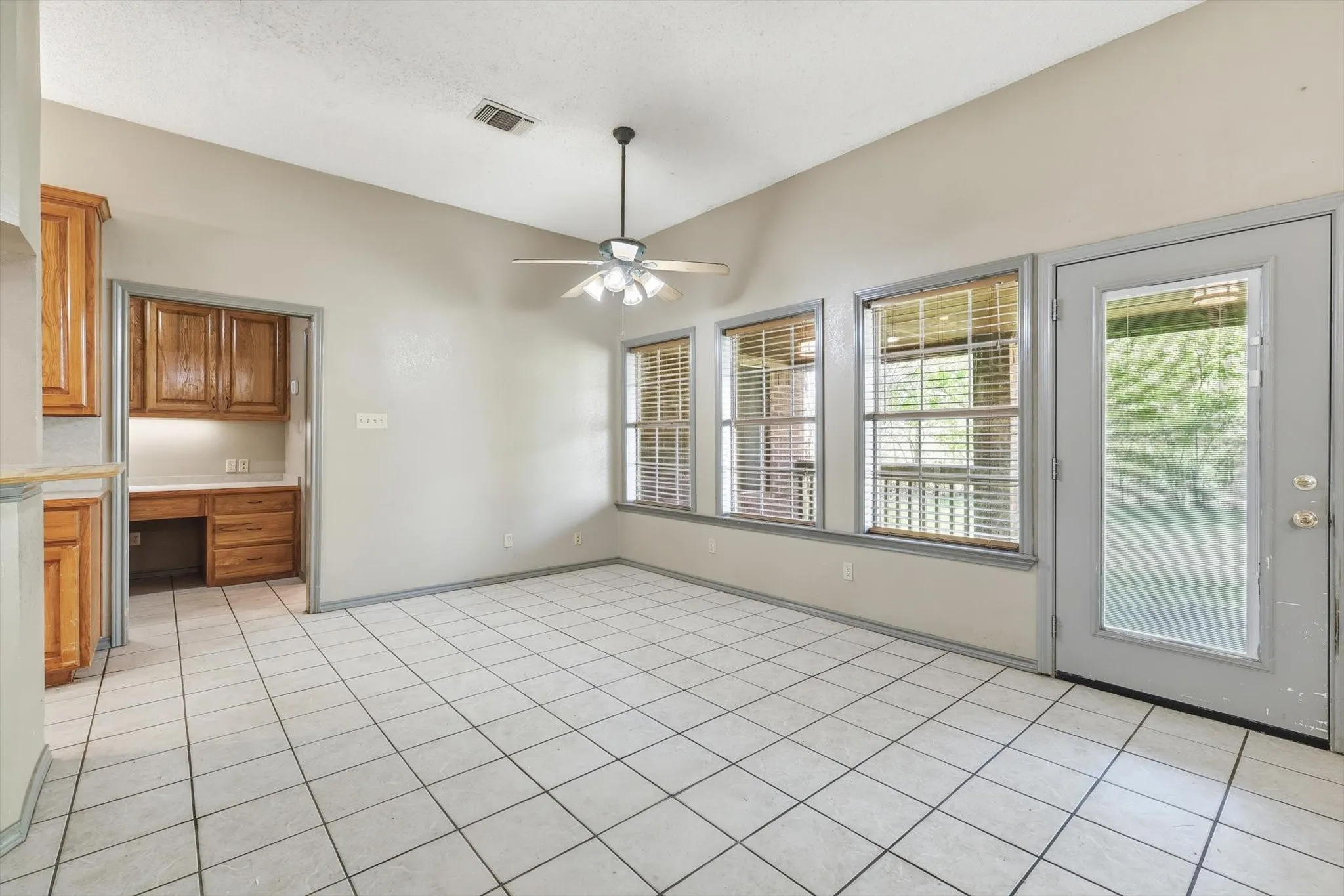 Unfurnished dining area featuring built in study area, ceiling fan, light tile patterned flooring, and lofted ceiling