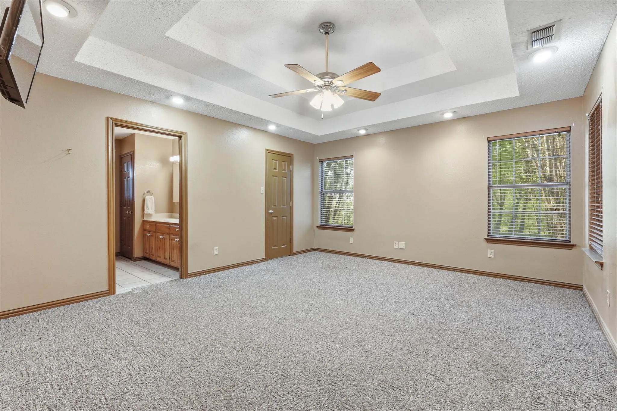 Unfurnished bedroom featuring recessed lighting, light colored carpet, a ceiling fan, and connected bathroom