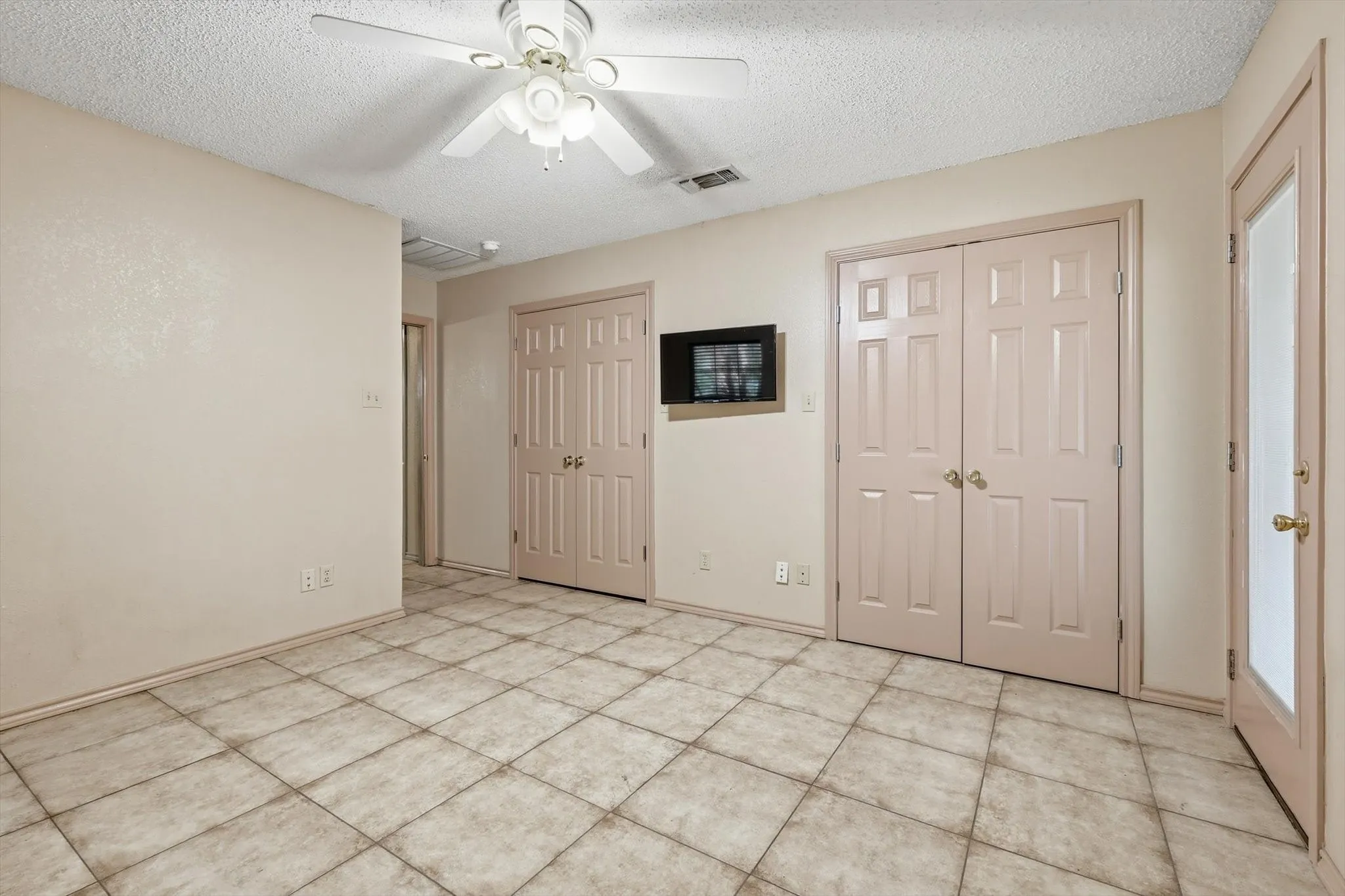 Unfurnished bedroom with multiple closets, a textured ceiling, and a ceiling fan