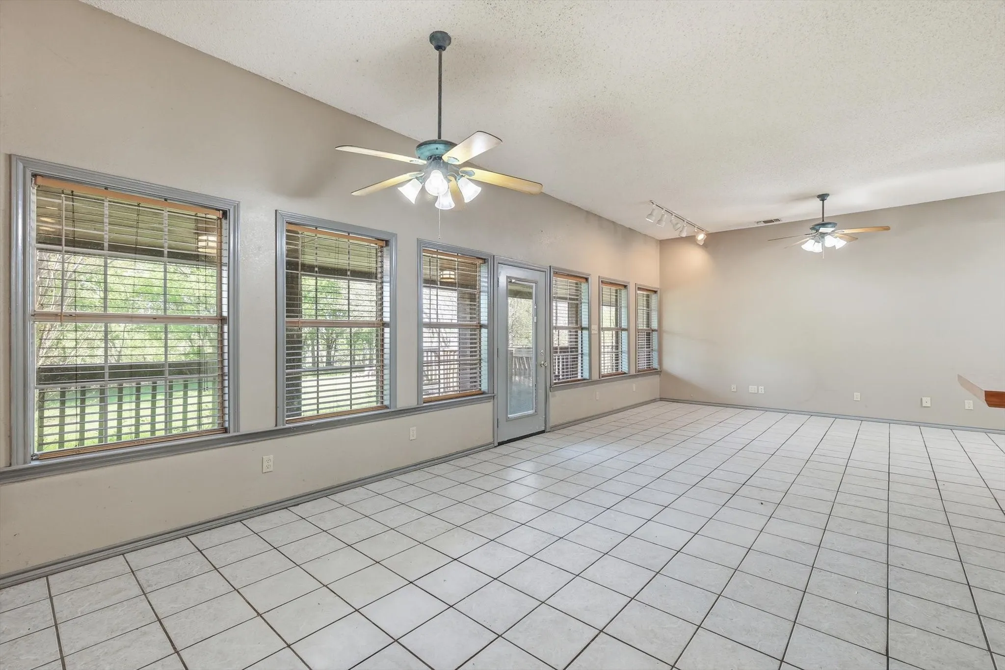 Empty room with a ceiling fan, rail lighting, and light tile patterned floors