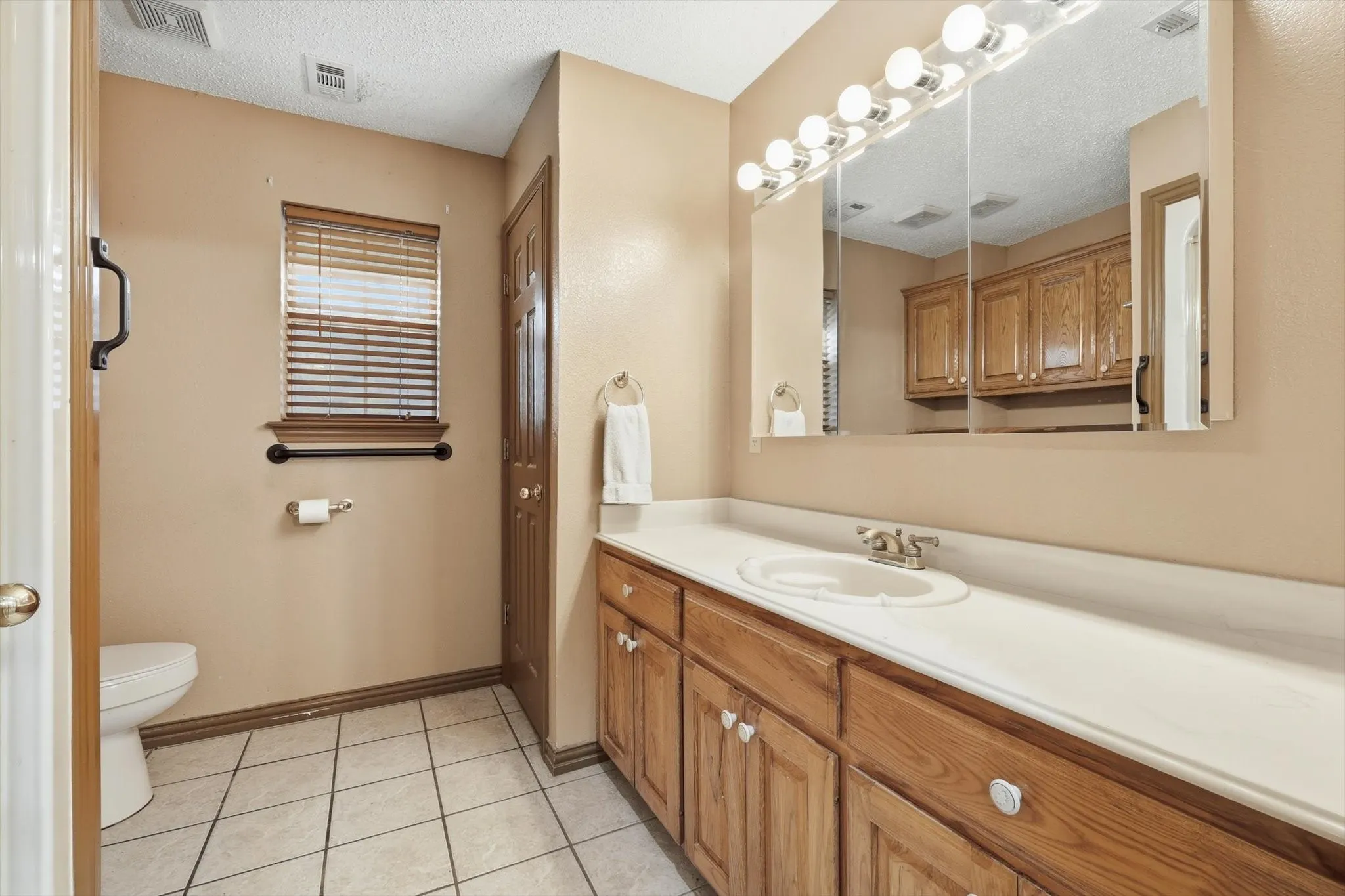 Full bath featuring vanity, a closet, a textured ceiling, and light tile patterned flooring