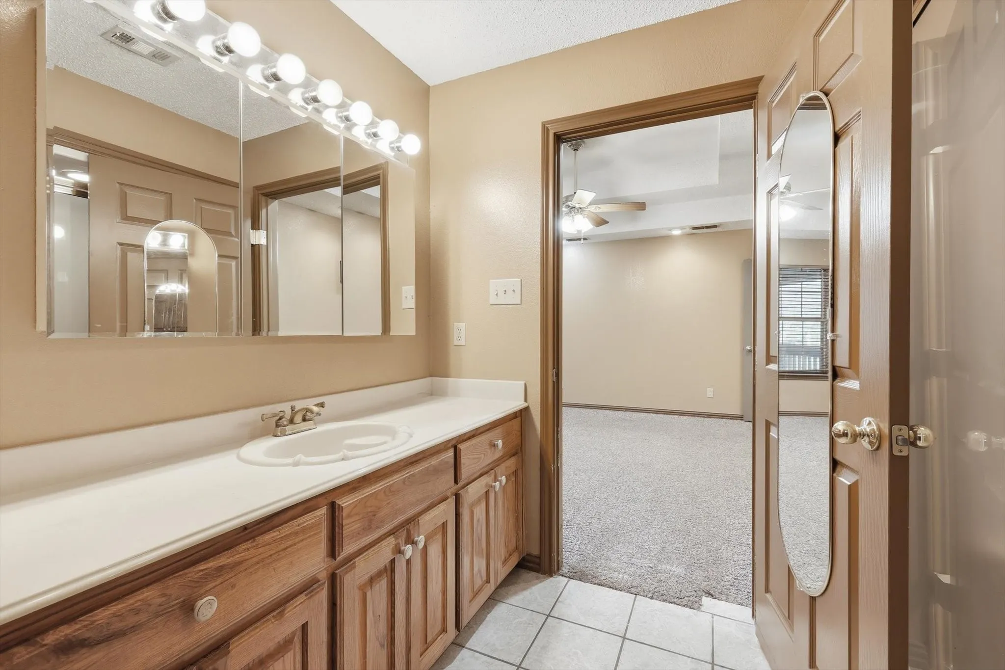 Bathroom featuring light colored carpet, vanity, light tile patterned floors, and a ceiling fan
