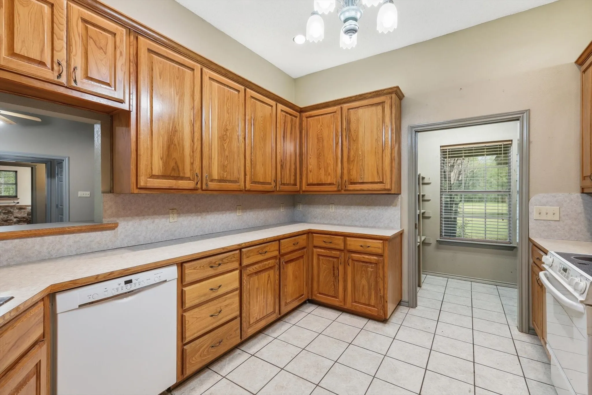 Kitchen featuring light countertops, white appliances, wood finish cabinets, and tasteful backsplash