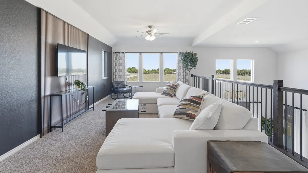 Living area featuring a ceiling fan, carpet flooring, healthy amount of natural light, and lofted ceiling