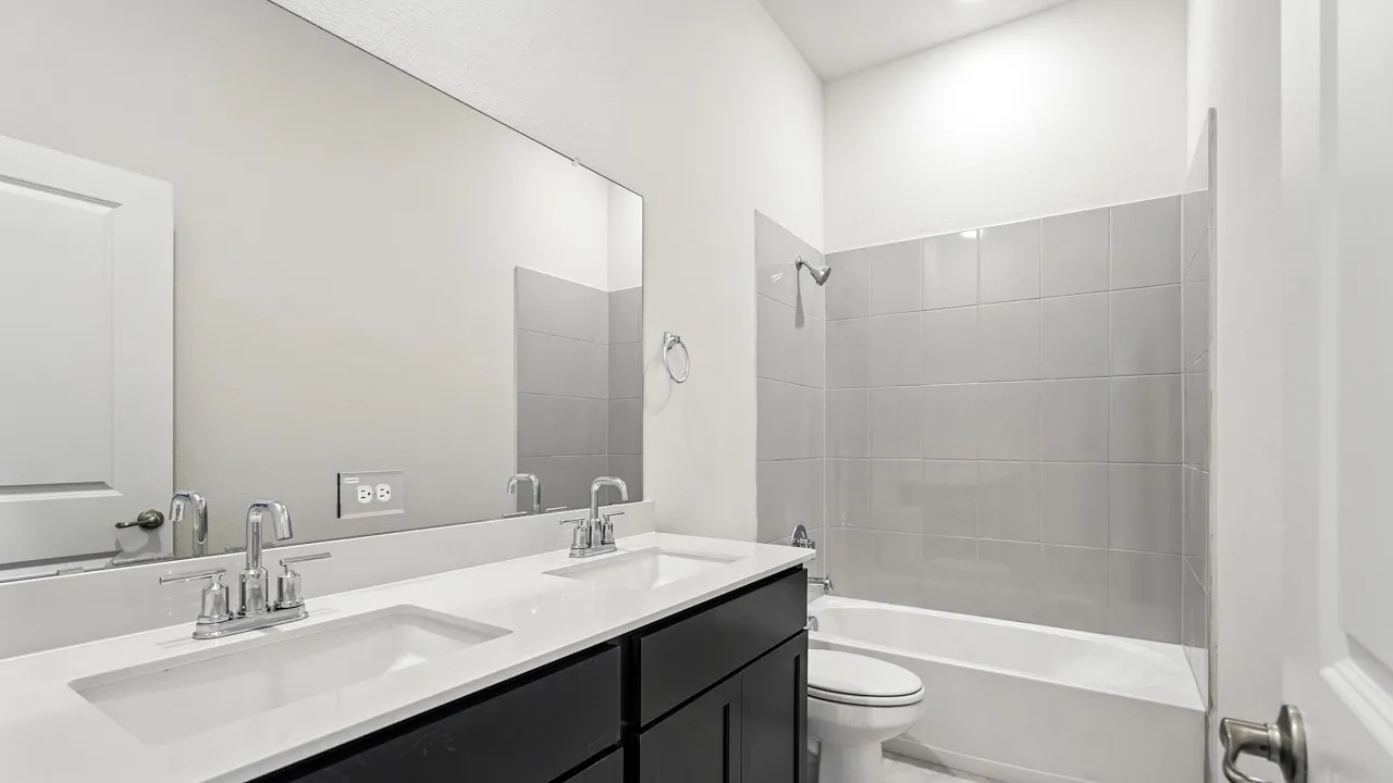 Bathroom featuring double vanity and shower / bathtub combination
