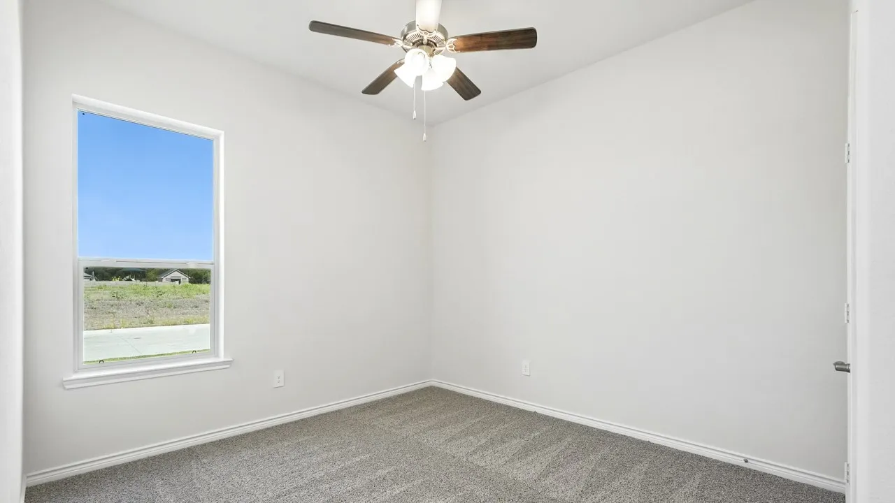 Carpeted spare room with baseboards and a ceiling fan