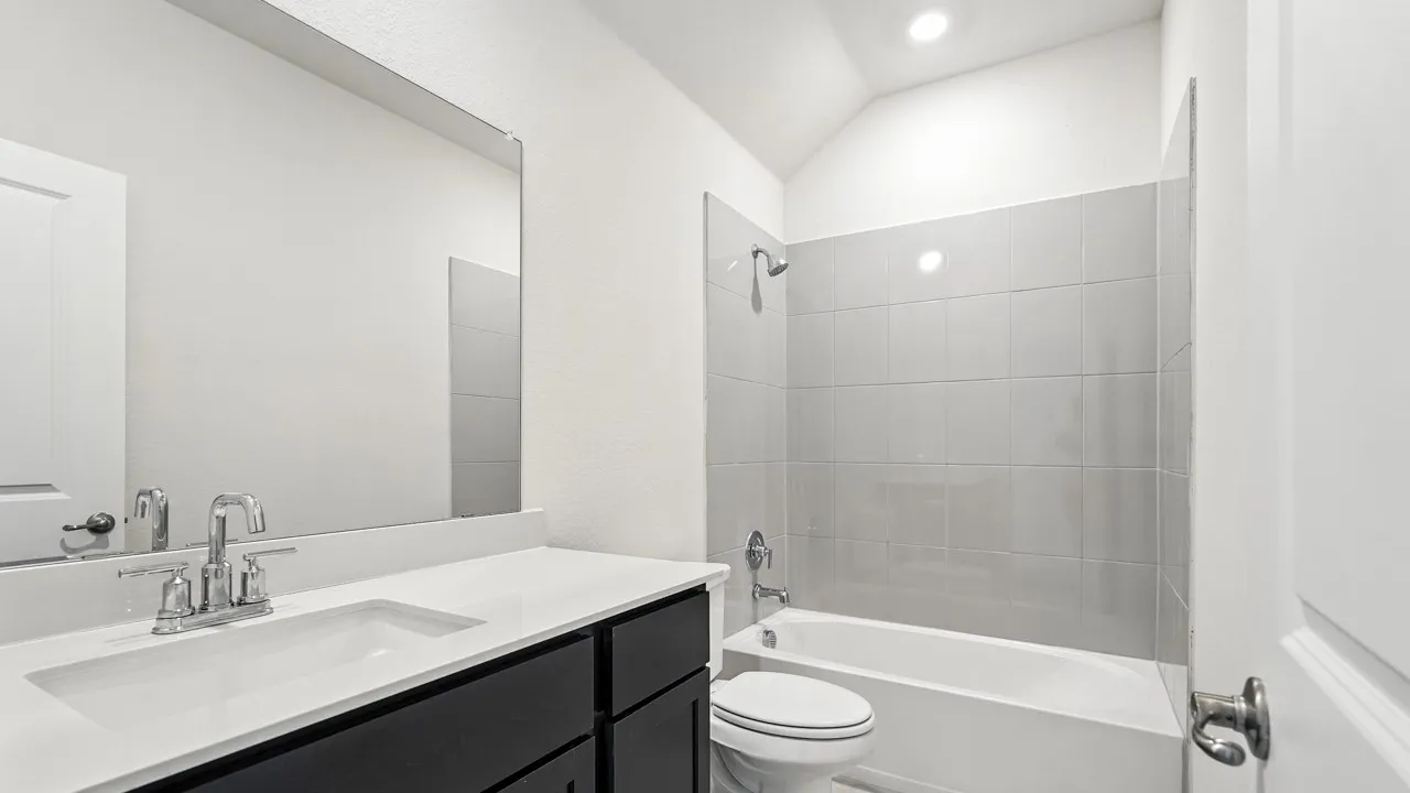 Bathroom with vanity, bathtub / shower combination, and vaulted ceiling