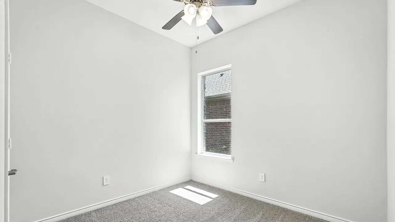 Carpeted spare room featuring a ceiling fan and baseboards