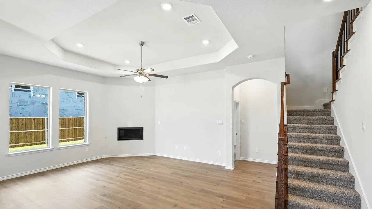 Unfurnished living room with arched walkways, a ceiling fan, recessed lighting, light wood-type flooring, and a glass covered fireplace