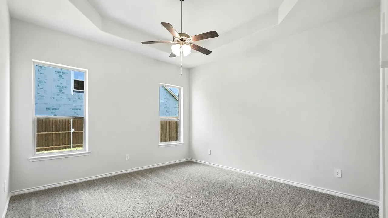 Carpeted spare room with a tray ceiling and a ceiling fan