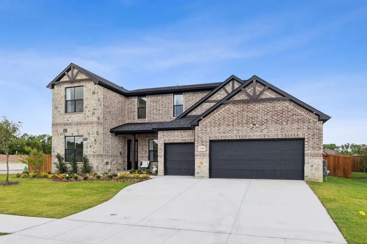 View of front facade featuring stone siding, a garage, concrete driveway, and brick siding