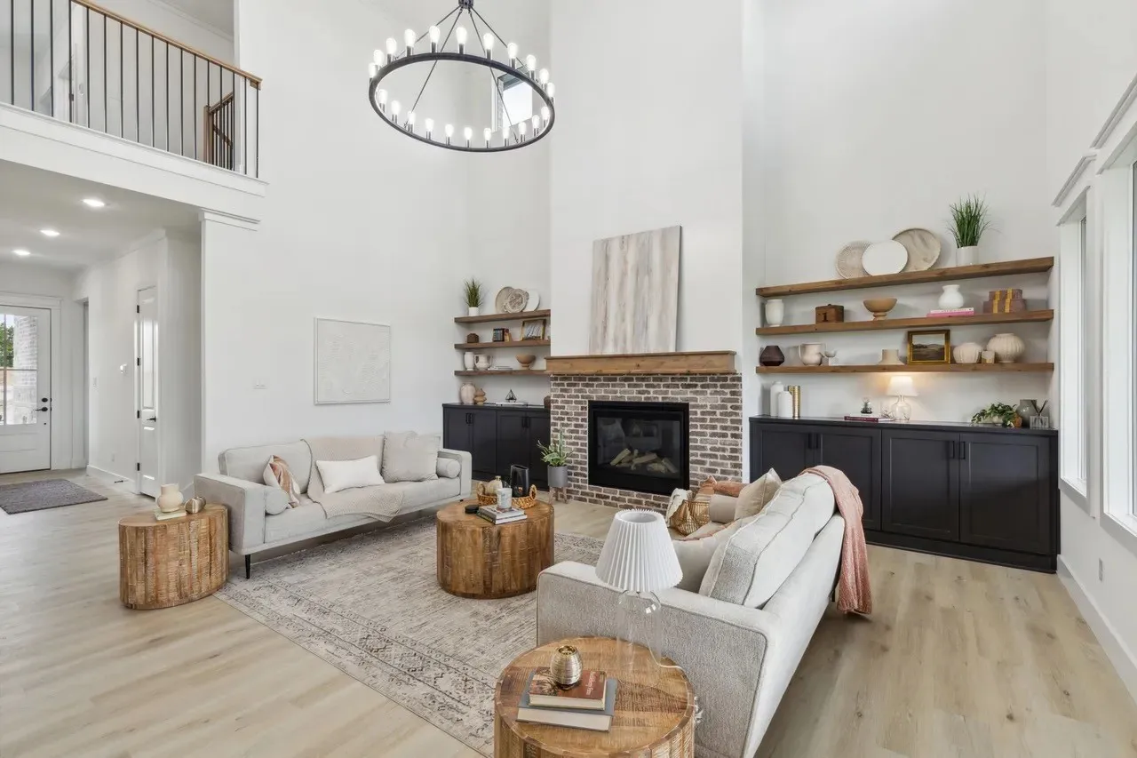 Living area featuring a high ceiling, light wood-style flooring, hanging lights, and a fireplace