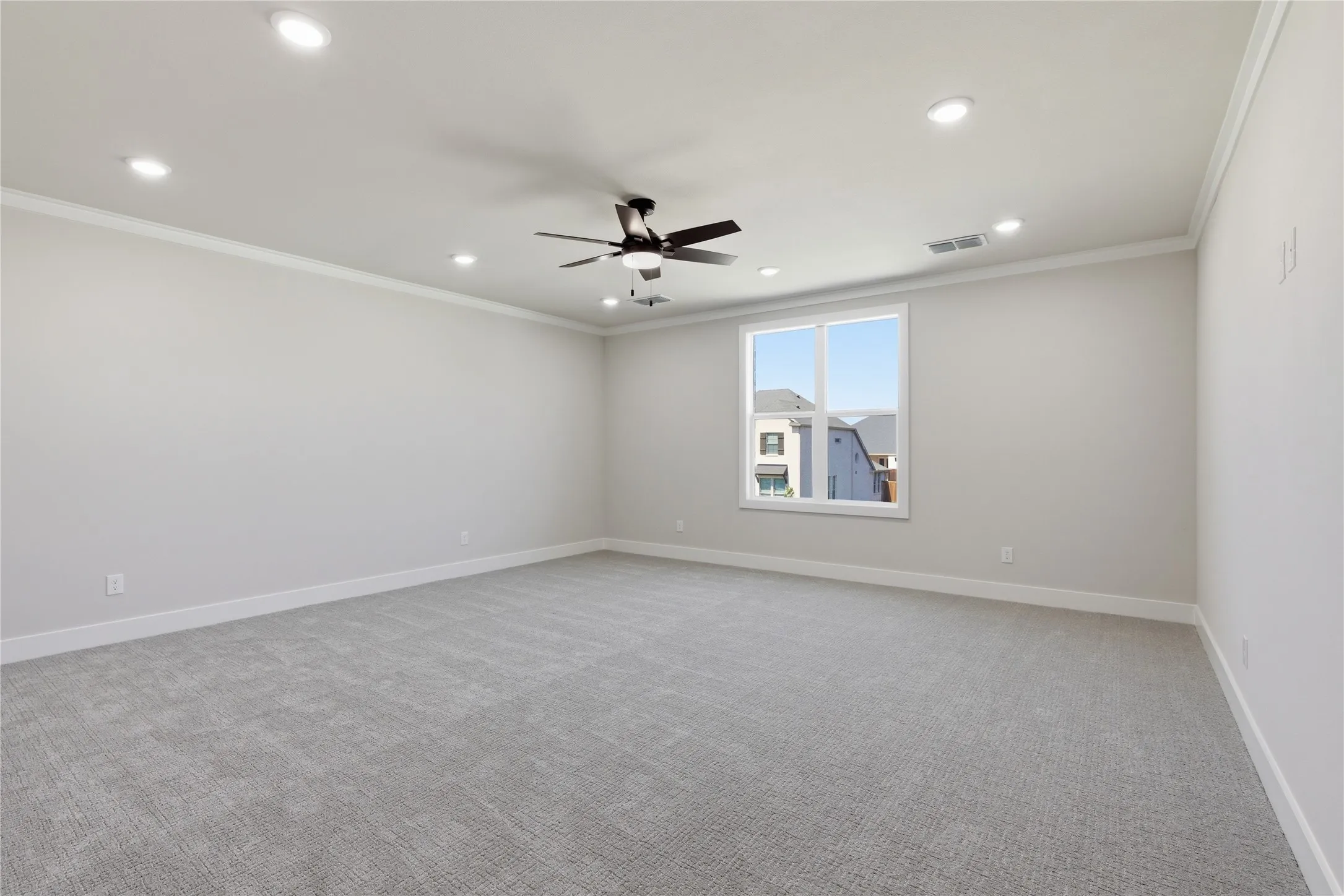 Spacious room featuring light gray carpeting, recessed lighting, a ceiling fan, crown molding, and a large window