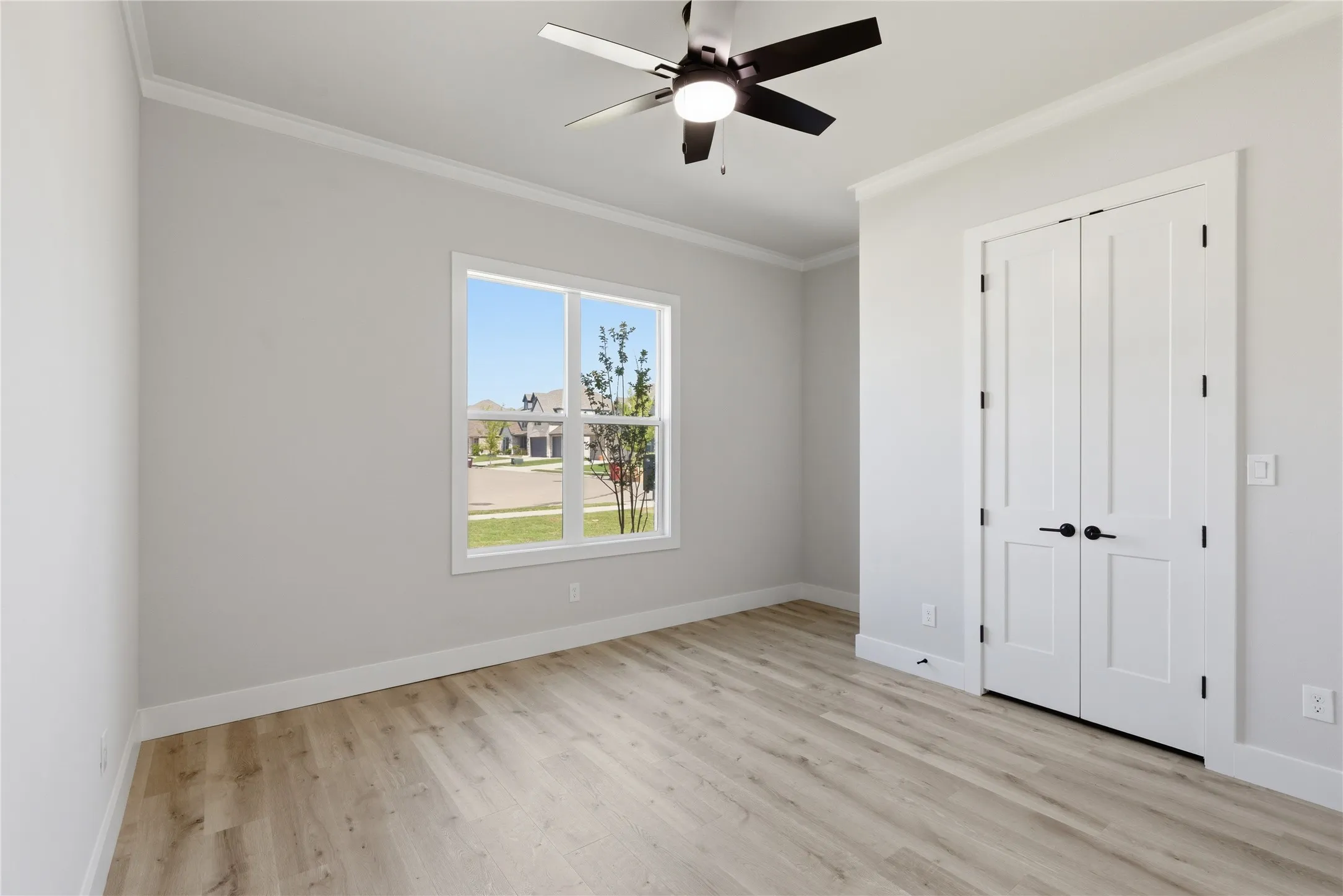 Bright room featuring wood-finish flooring, a contemporary ceiling fan, and a large window with white trim