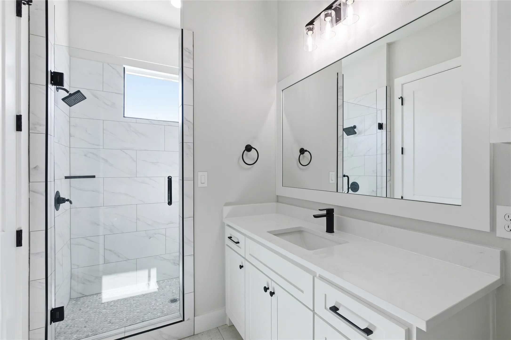 White vanity with a single basin sink, matte black faucet, and white countertop