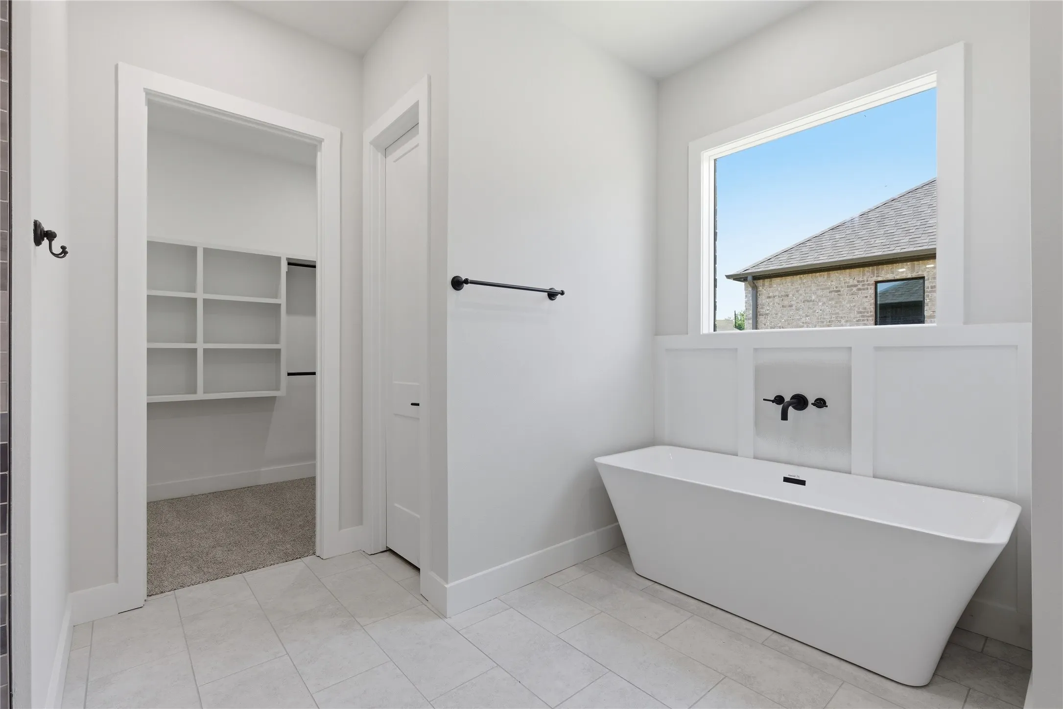 Freestanding soaking tub with wall-mounted matte black fixtures