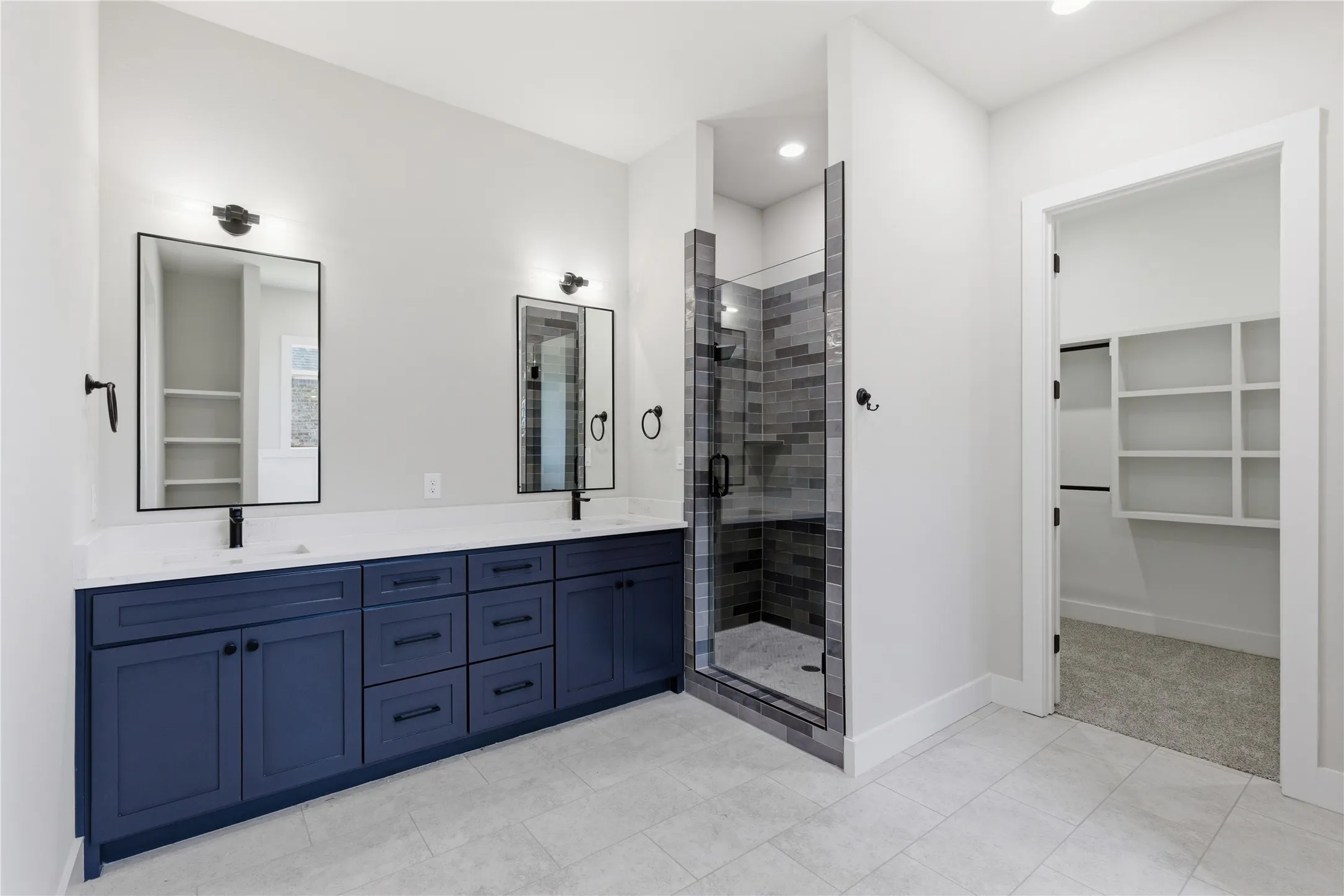 Bathroom featuring a dual vanity with navy cabinetry, matte black hardware, and rectangular mirrors
