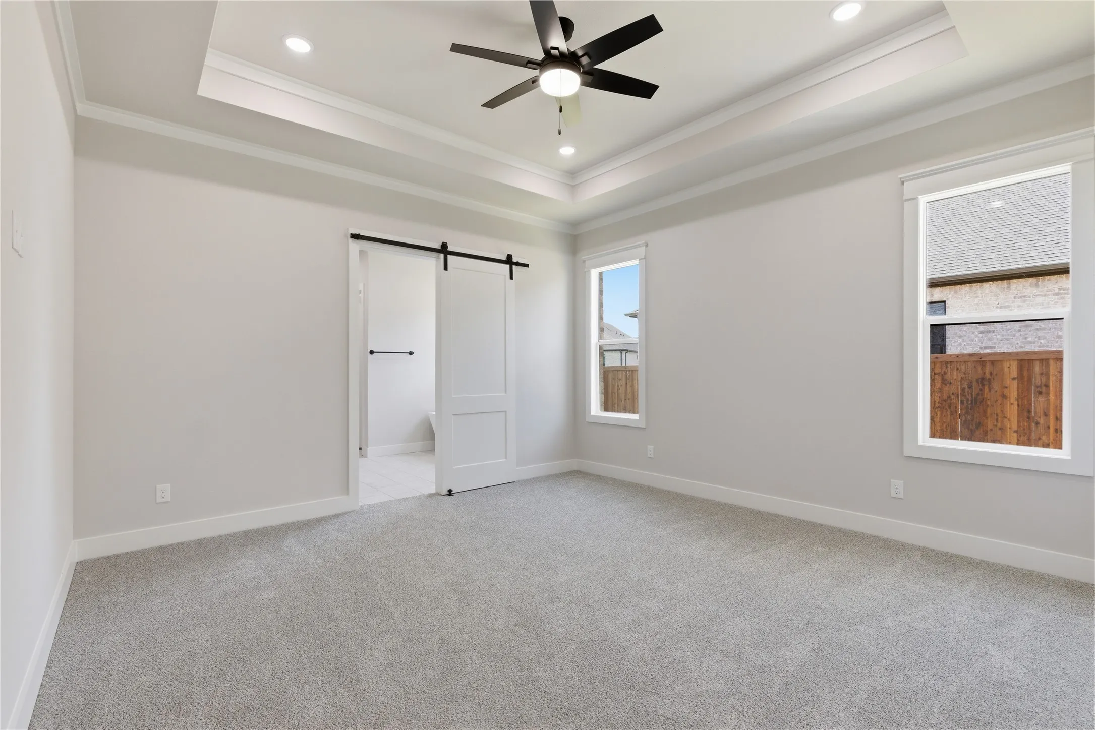 Spacious room featuring light gray carpeting, recessed ceiling lighting, a contemporary ceiling fan, and two large windows