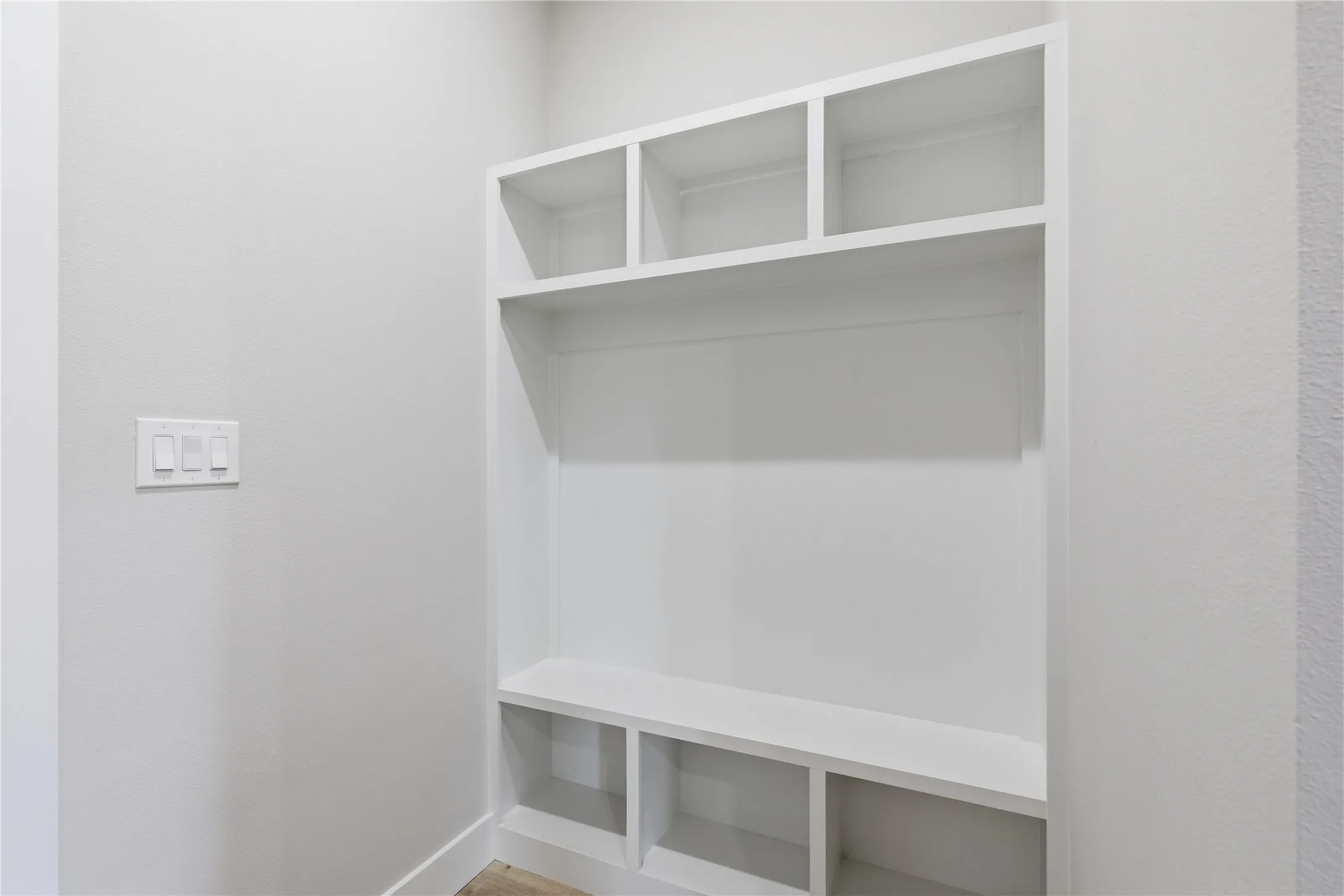 Built-in white shelving unit with varied cubby sizes, a broad central shelf, and lower compartments