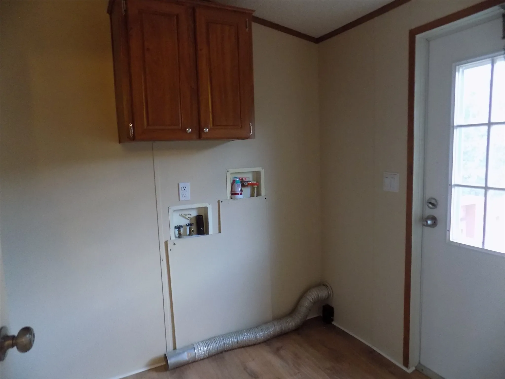 Laundry room with washer and dryer hookups, wood finished floors, and convenient cabinet space overhead.