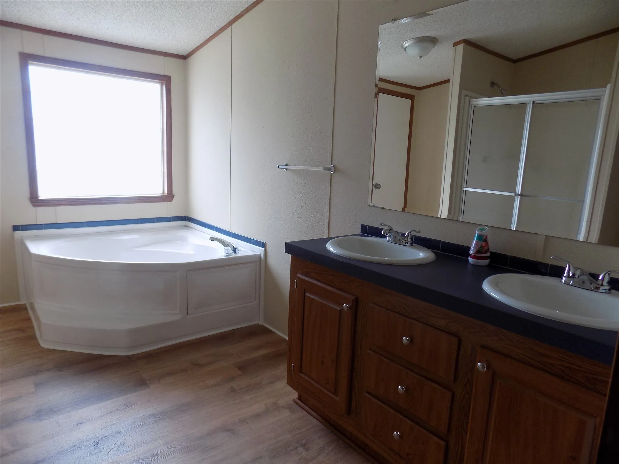 Another view of primary bathroom, with natural light, dual sinks and a lovely garden tub.