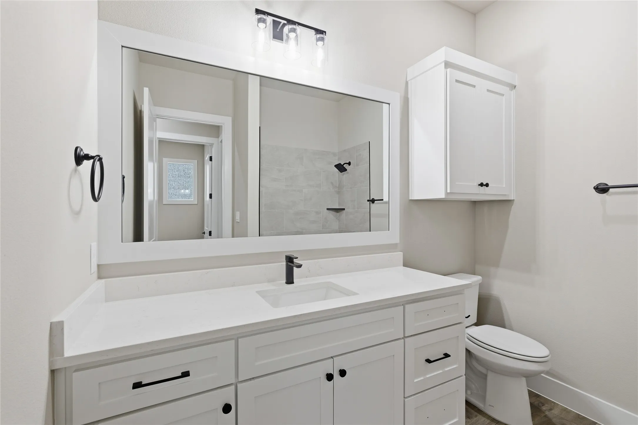 Contemporary bathroom featuring an expansive single vanity with a white countertop and integrated sink, matte black faucet, and a large framed mirror