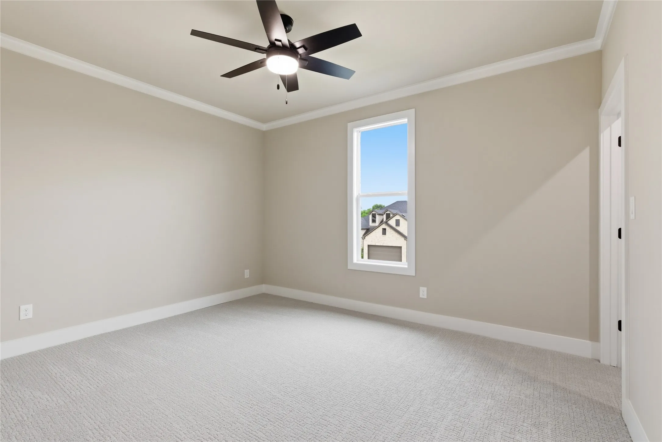 Carpeted interior room featuring neutral wall tones, white trim, and a ceiling fan with integrated lighting