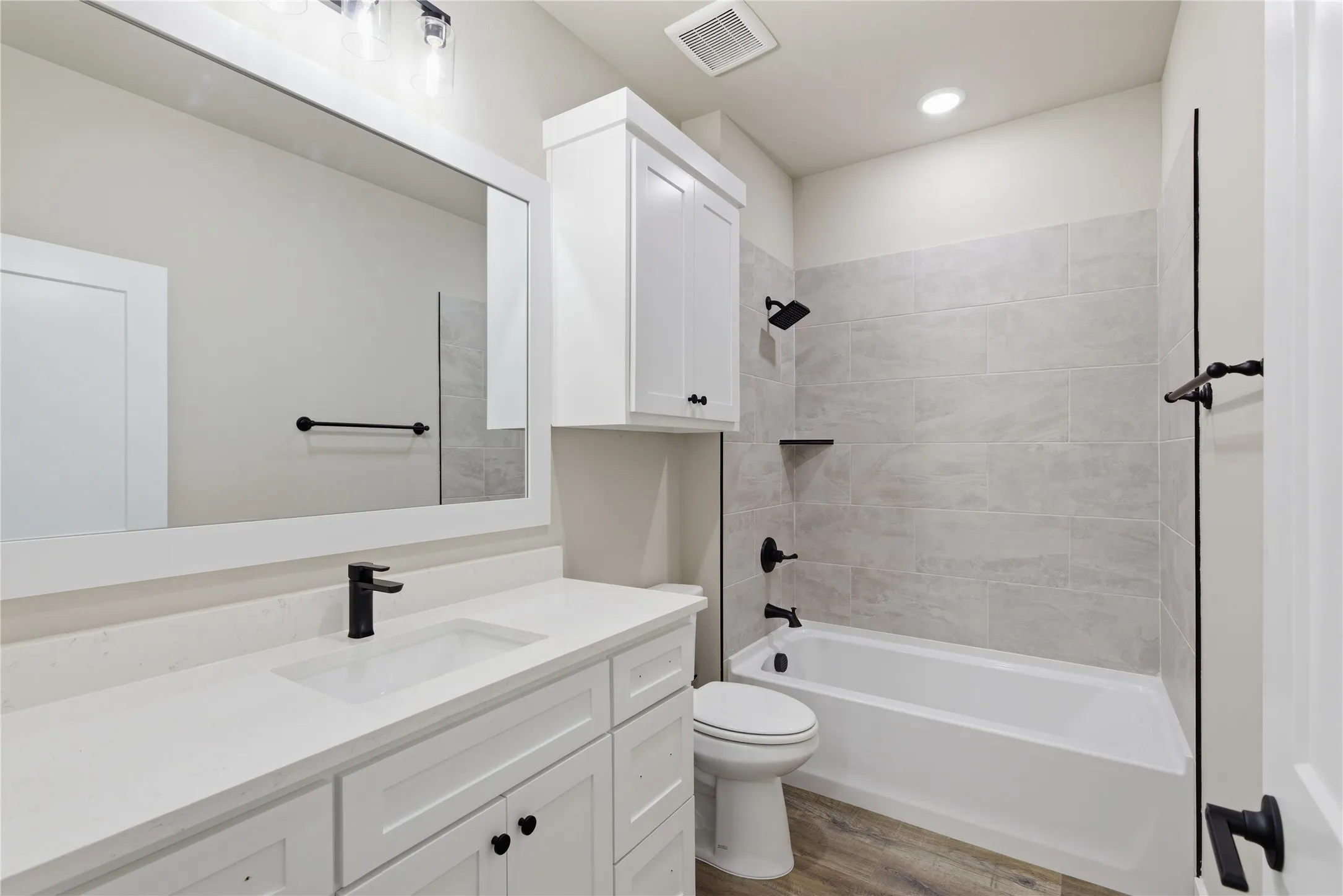 Contemporary bathroom featuring a white vanity with quartz countertop, undermount sink, and matte black faucet