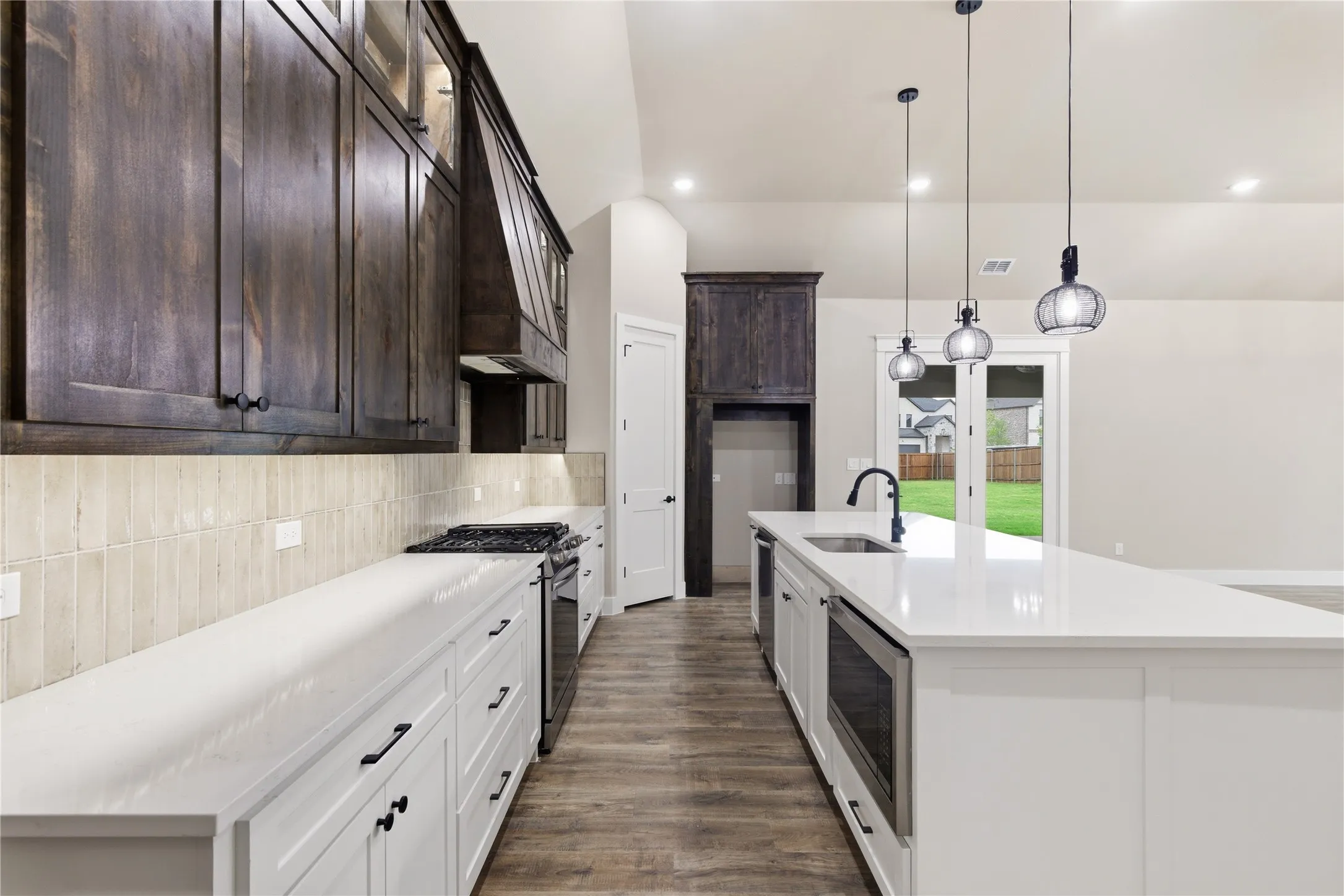 Kitchen featuring dark wood-finish upper cabinetry, white lower cabinetry, and an expansive white countertop island