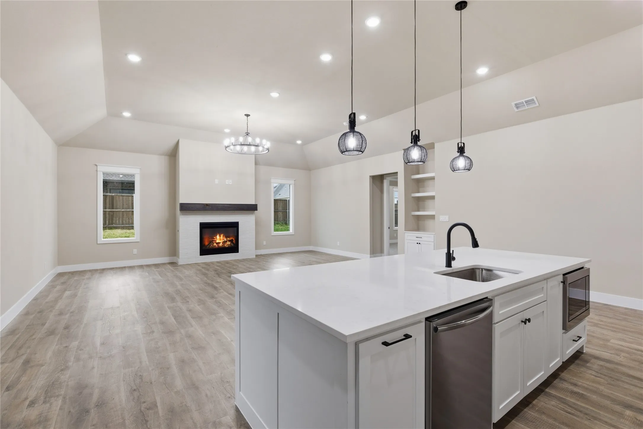 Open-concept living space featuring a central kitchen island with a built-in sink and stainless steel appliances