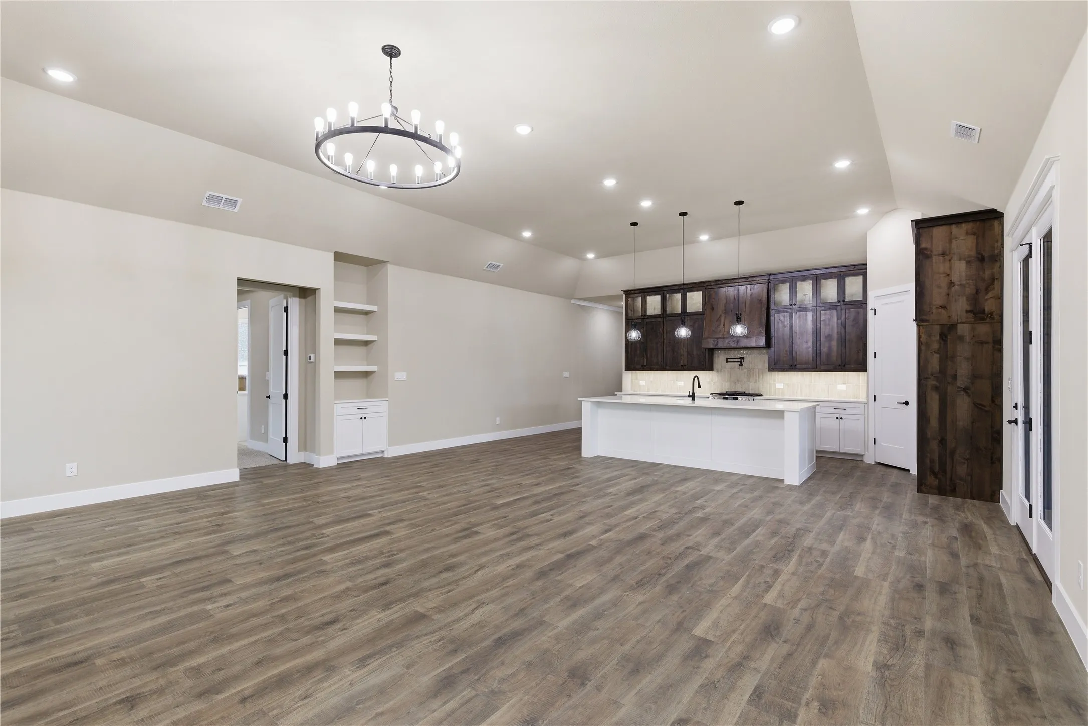 Open-concept living area featuring wood-finish flooring, recessed lighting, and a contemporary chandelier