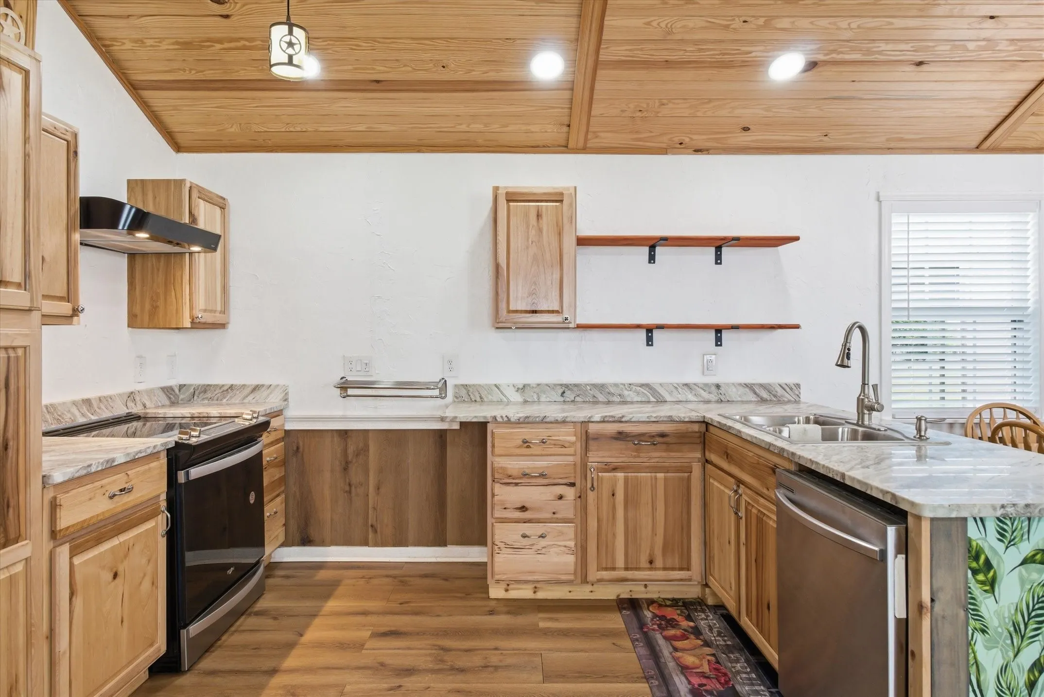 Kitchen with a peninsula, stainless steel appliances, dark wood-style flooring, wooden ceiling, and light stone counters
