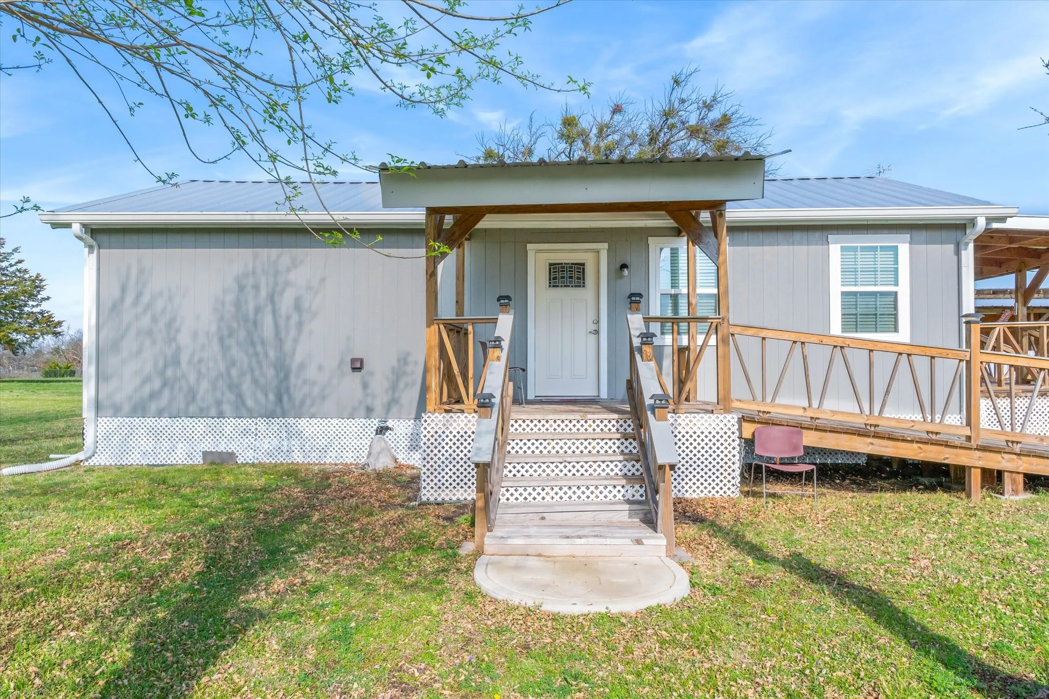 Front of home with a metal roof, a front lawn, and a wooden deck