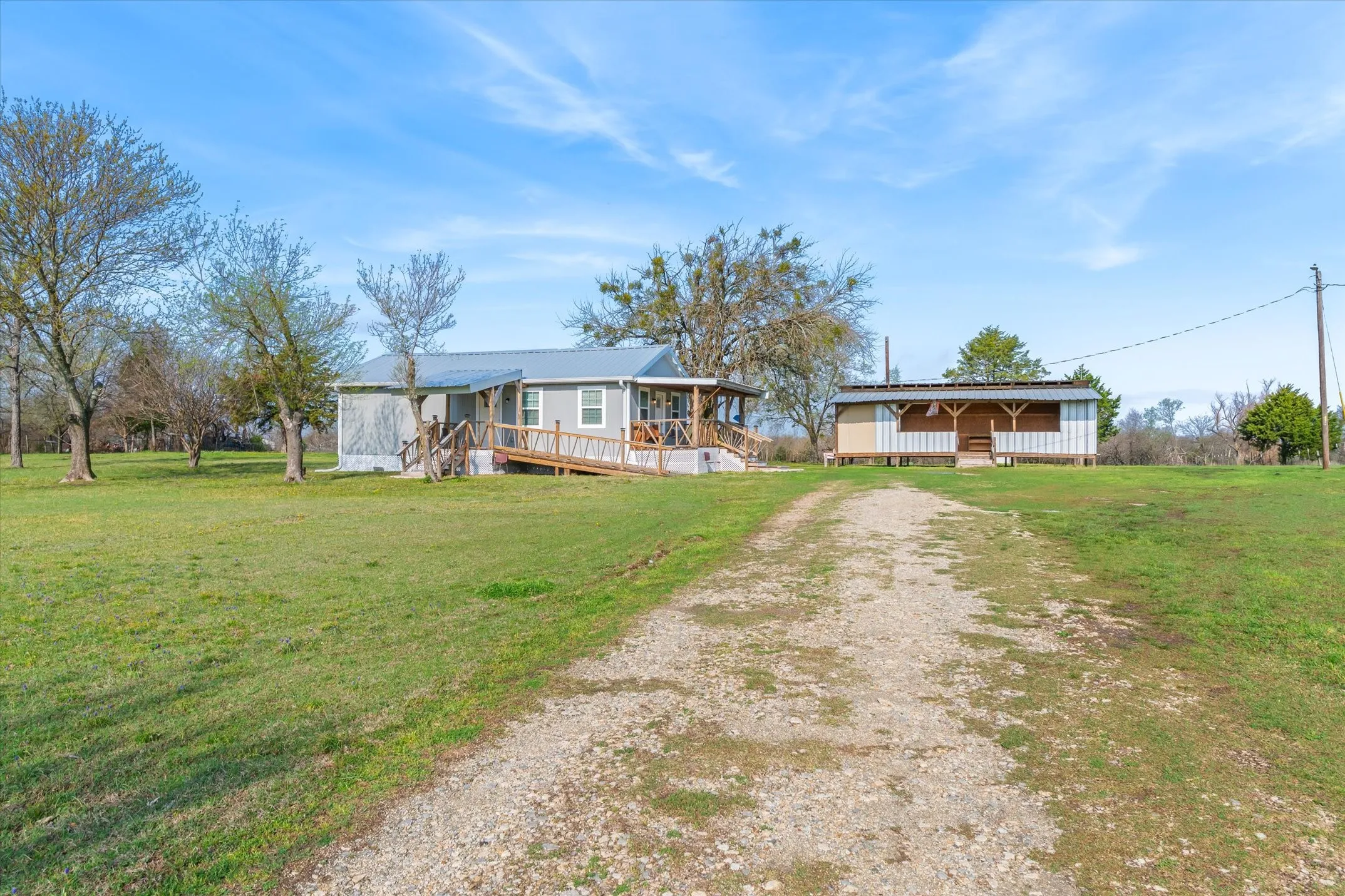 View of front facade with a front yard, a wooden deck, and driveway